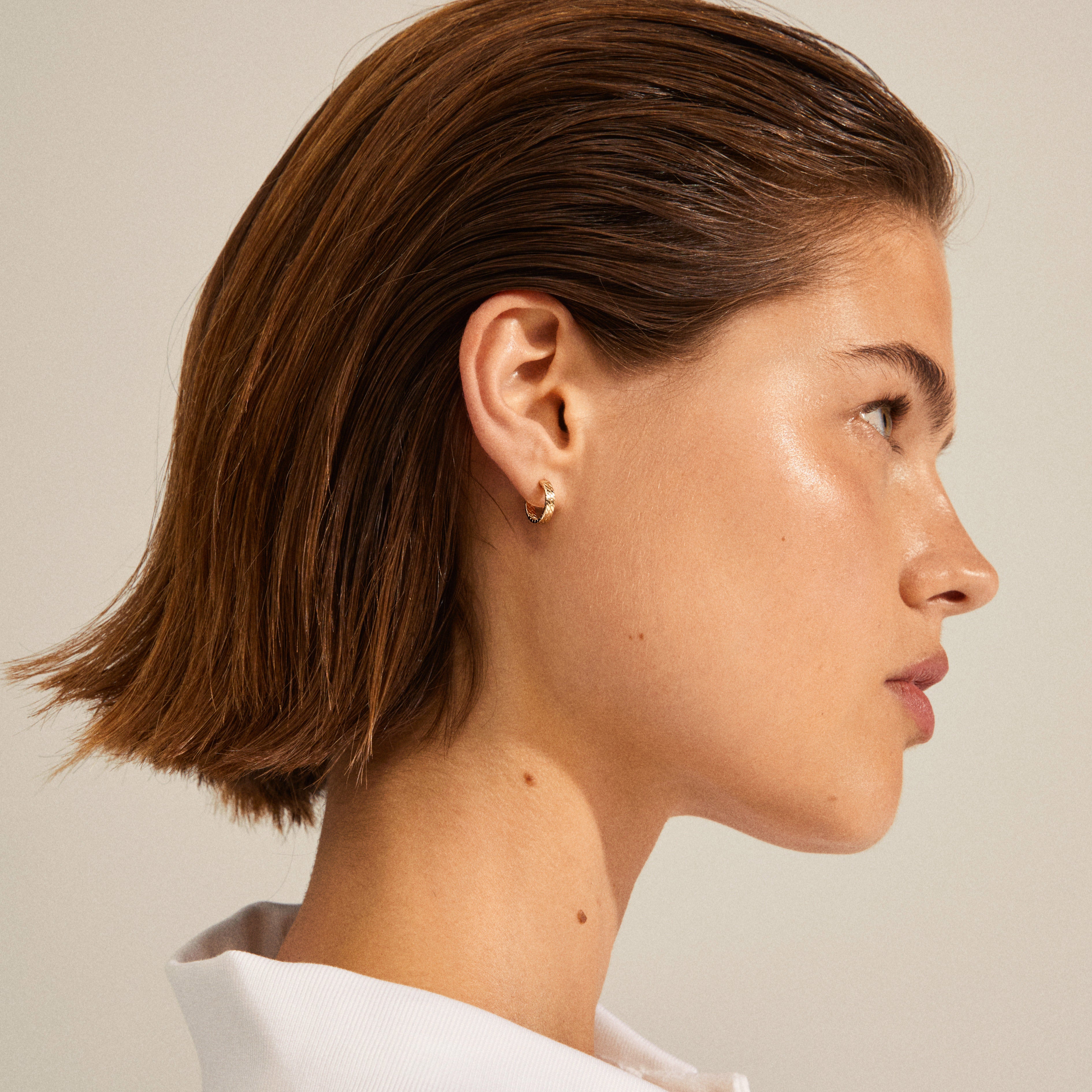Woman wearing JOANNA snake chain hoop earrings, gold-plated with a raw chain structure, capturing a stylish Nordic look.