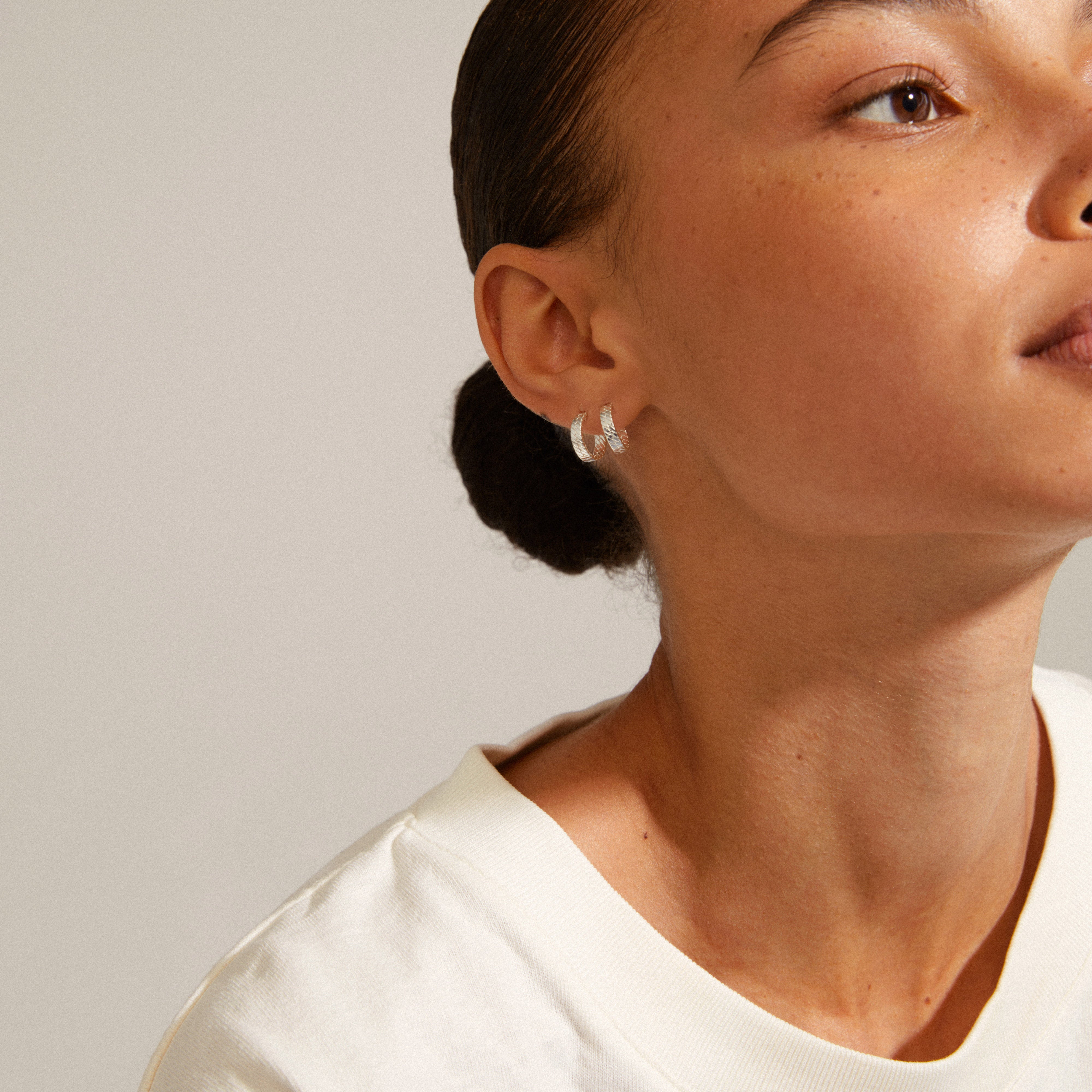Silver-plated JOANNA snake chain hoop earrings on a woman, showcasing their urban chain-inspired texture and shiny surface, embodying Nordic aesthetics.