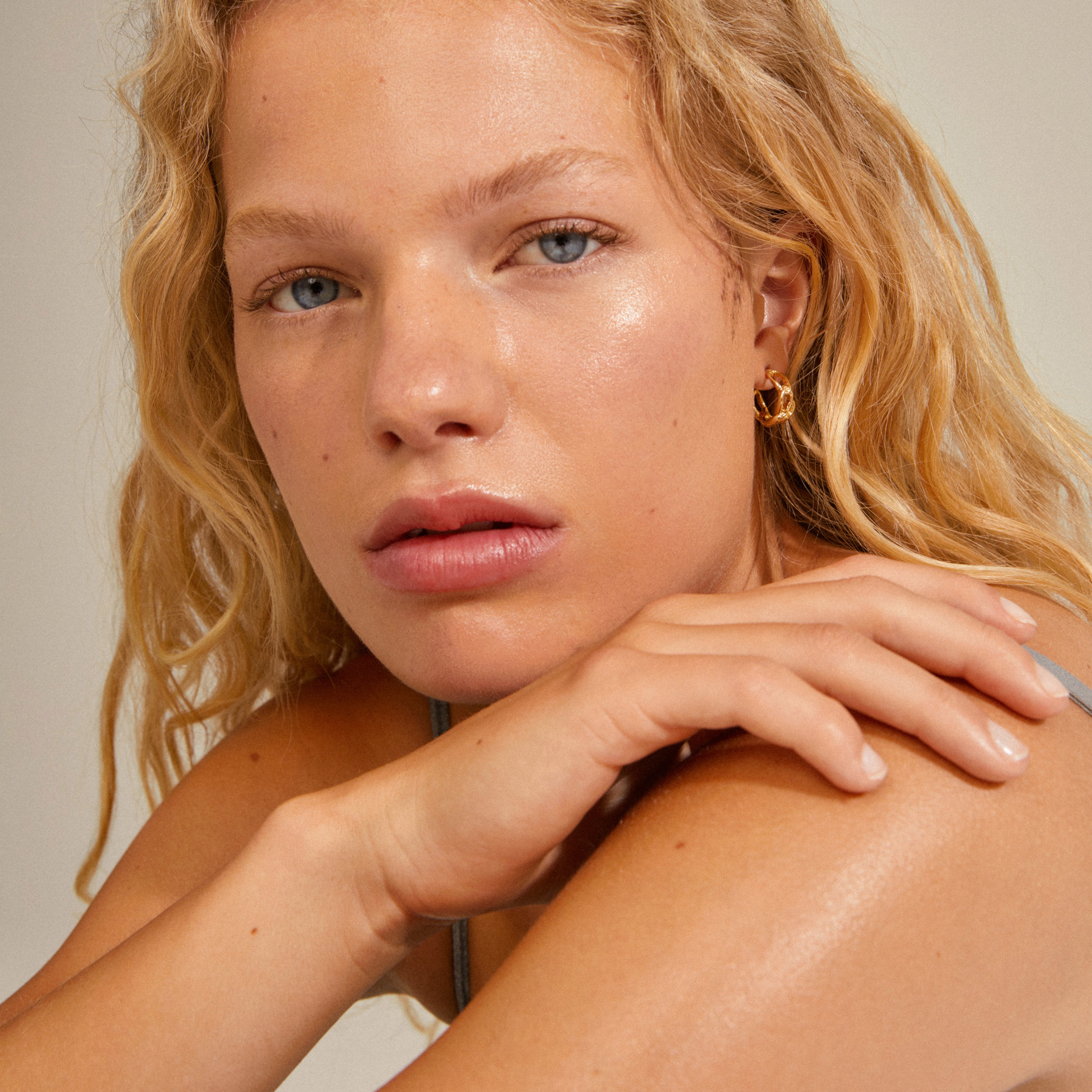 Close-up of a woman wearing RANI earrings, gold-plated hoops with a delicate design, highlighting Pilgrim's classic and sustainable style.