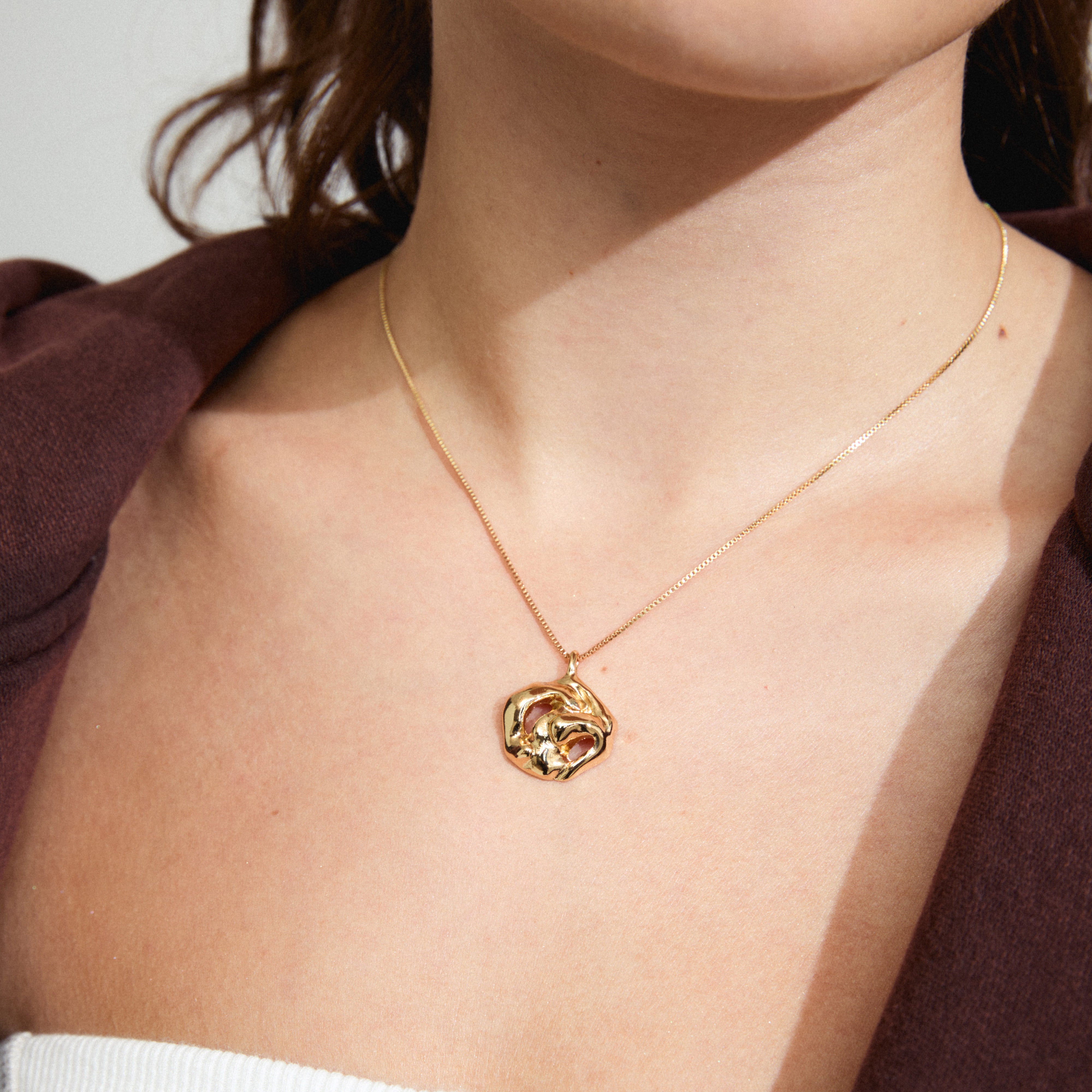 Woman wearing LUCA necklace gold-plated with a distinctive melting-shaped pendant, showcasing Pilgrim's eco-friendly, stylish Danish design. Perfect for adding a personal touch to outfits.