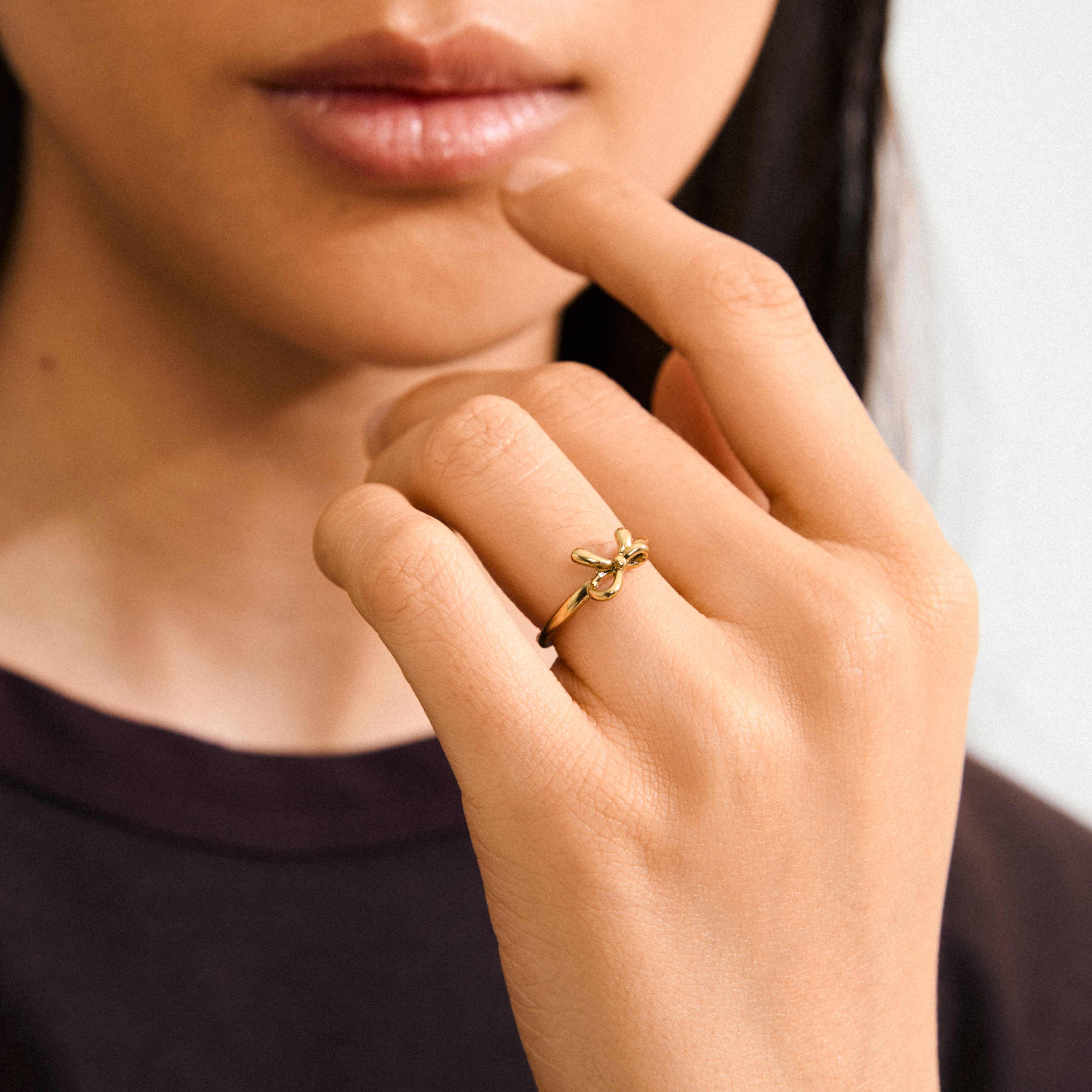 Close-up of a woman's hand wearing the LULU bow stack ring, gold-plated, showcasing its sleek, romantic design from Pilgrim's Lulu collection.