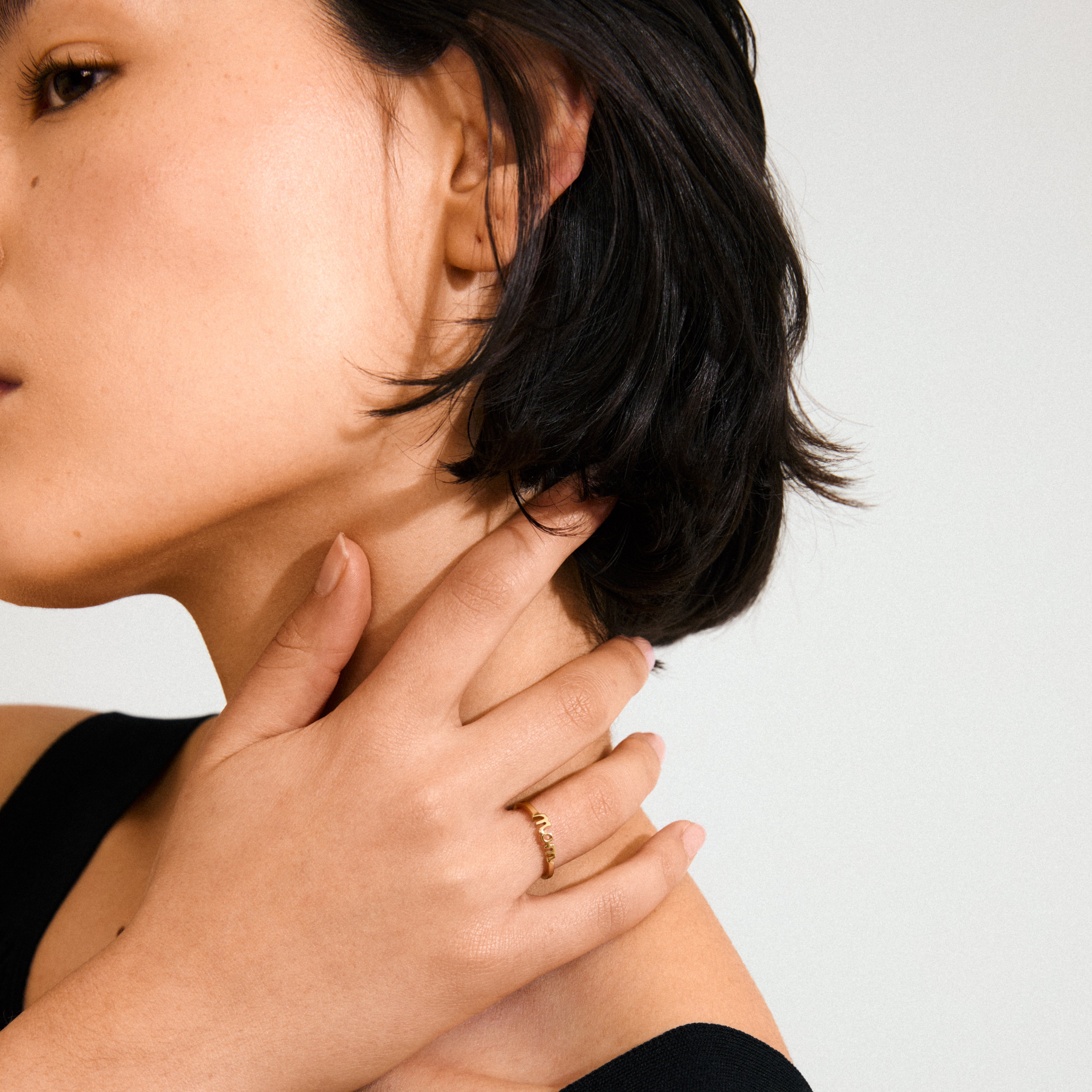 Close-up of a woman's hand showcasing the LULU mom stack ring, a gold-plated, elegant tribute to motherhood and family, crafted from 99% recycled materials.
