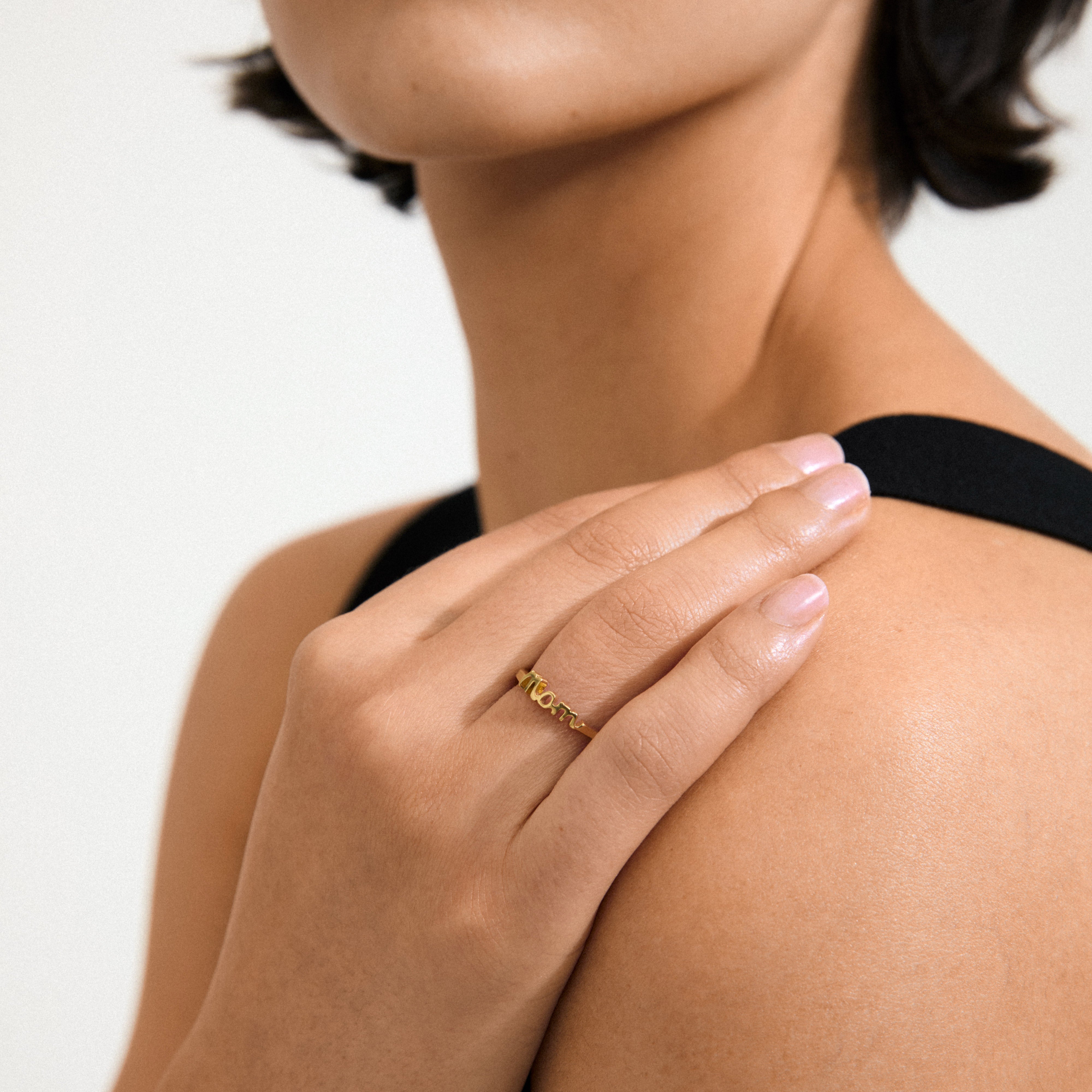 LULU mom stack ring gold-plated on woman's hand, featuring 'Mom' inscription. Elegant design, perfect for gifting or personal style, made from 99% recycled material.