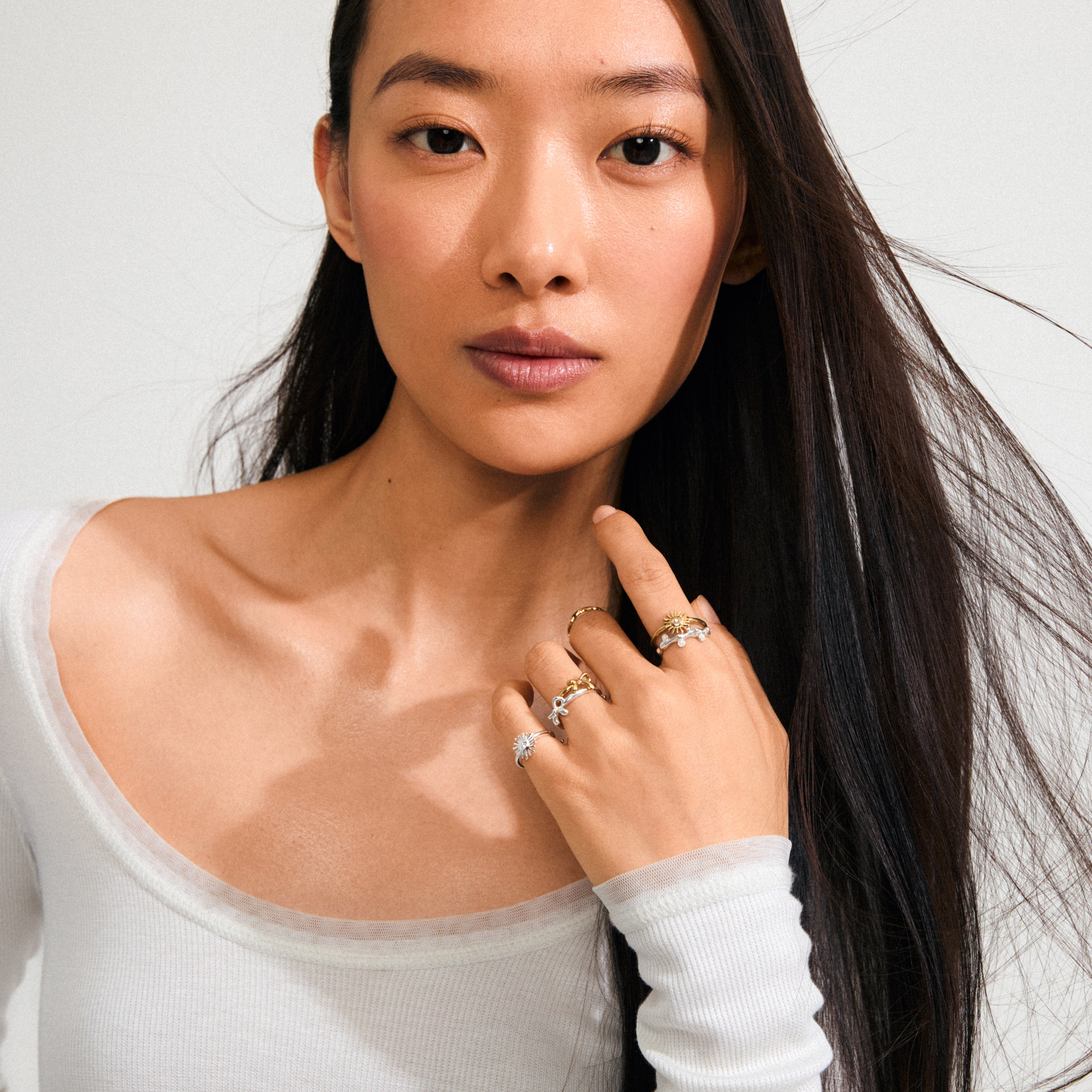 Young woman wearing several rings, including the gold-plated LULU mom stack ring with 'Mom' inscription, showcasing a blend of trendy and timeless Pilgrim jewelry.