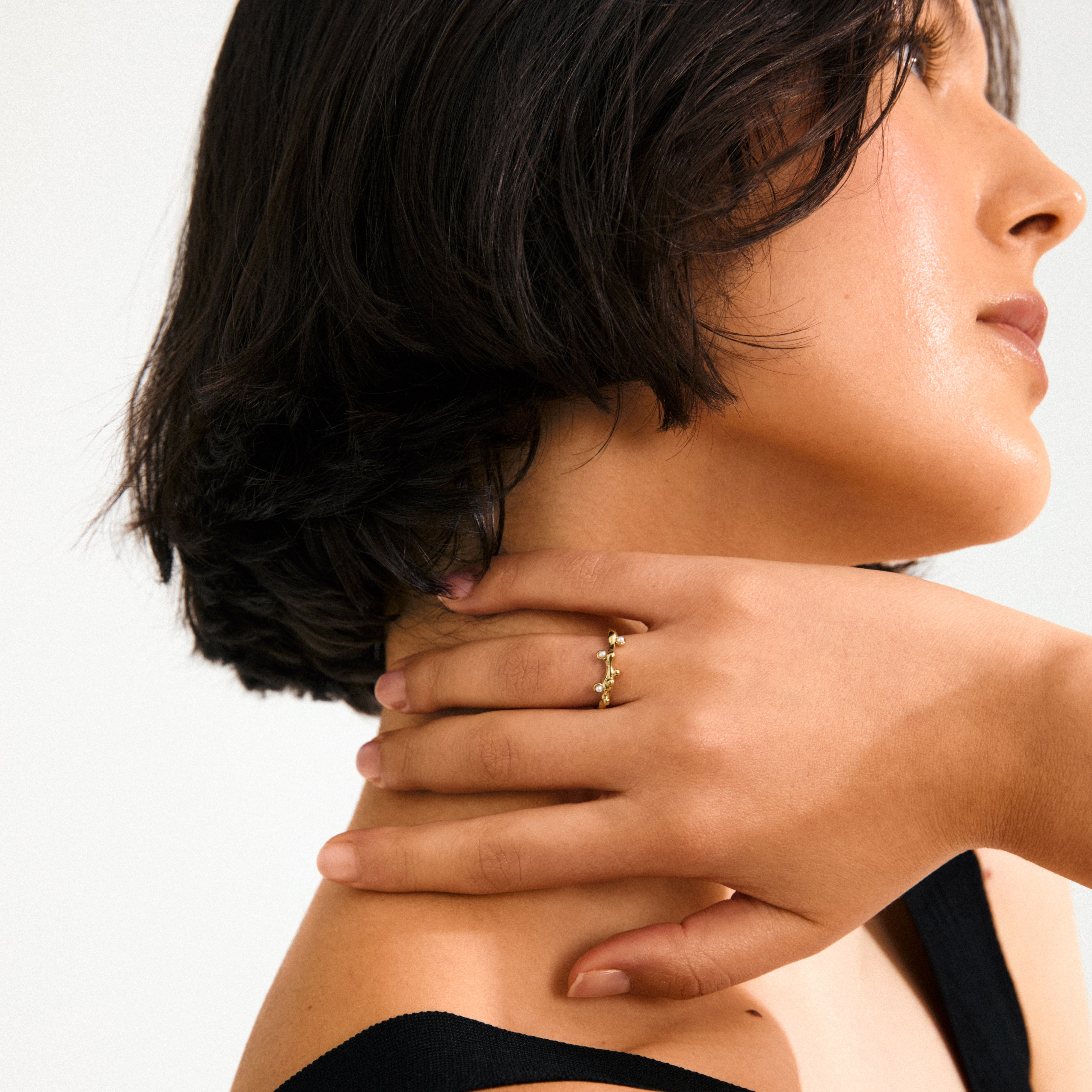 Gold-plated Lulu magic stack ring with organic design, featuring mother-of-pearl beads like dewdrops on a twig, crafted from recycled materials.