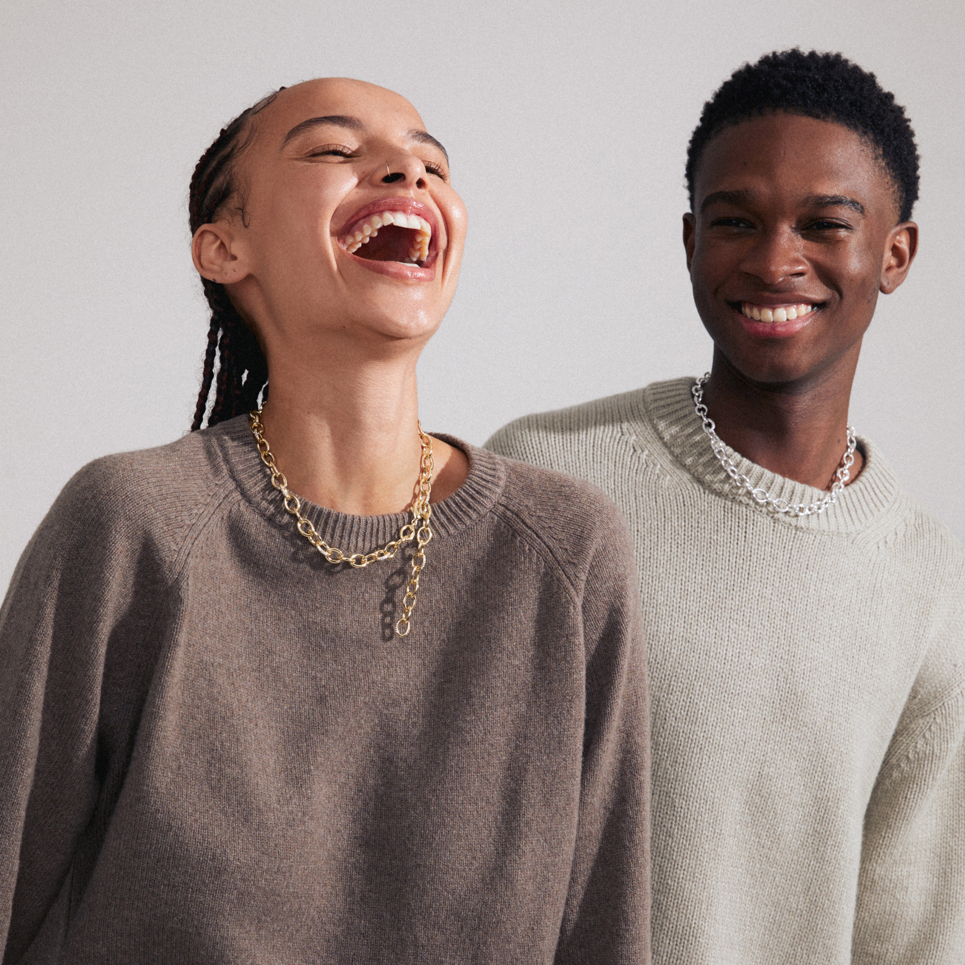 AMIRI gold-plated necklace on laughing woman, featuring a modern cable chain design with Preciosa crystals, embodying timeless elegance and Scandinavian craftsmanship.