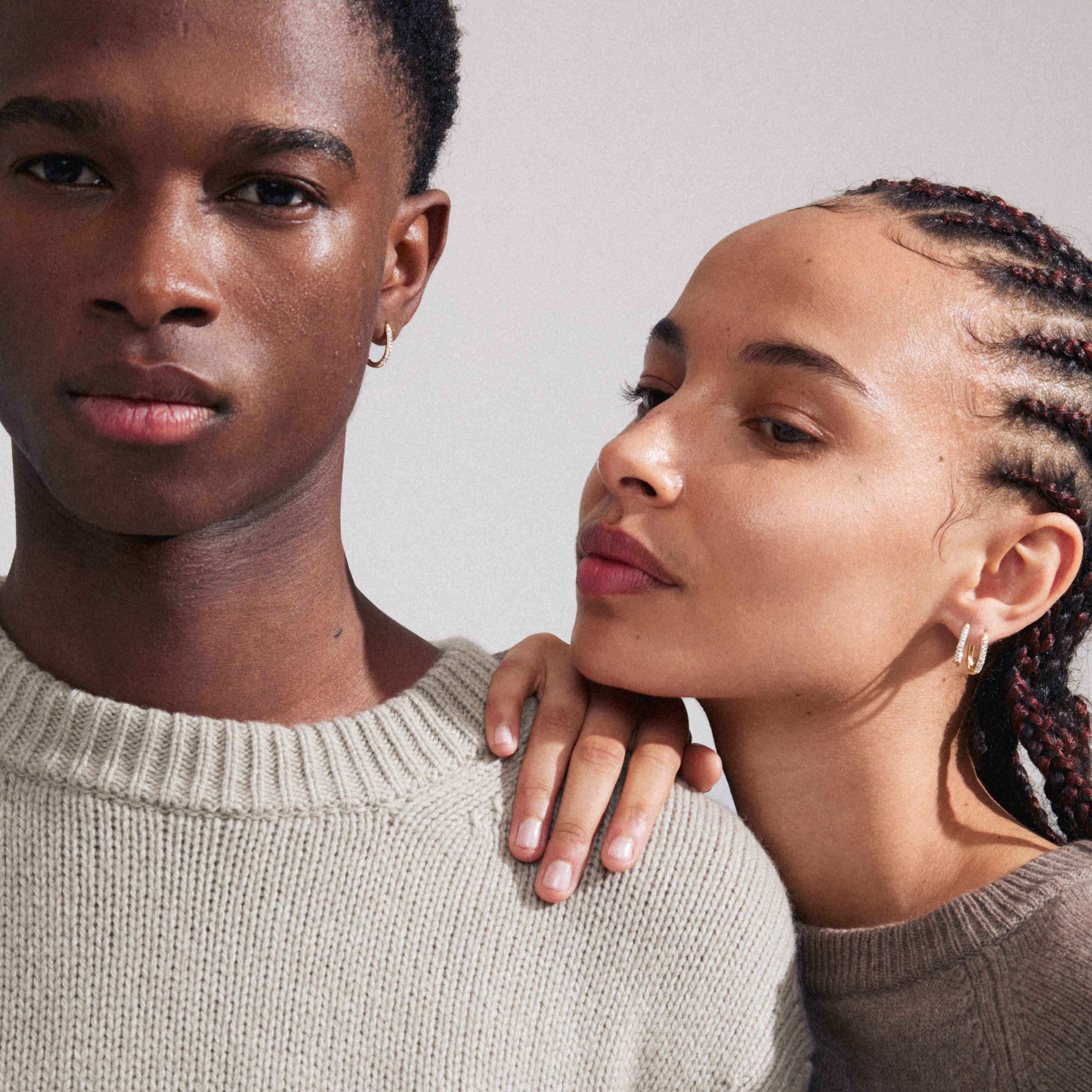AMIRI gold-plated earrings featuring sparkling Preciosa crystals, worn by a woman with braids. Elegant oval design with easy click clasp, stylish and sustainable.