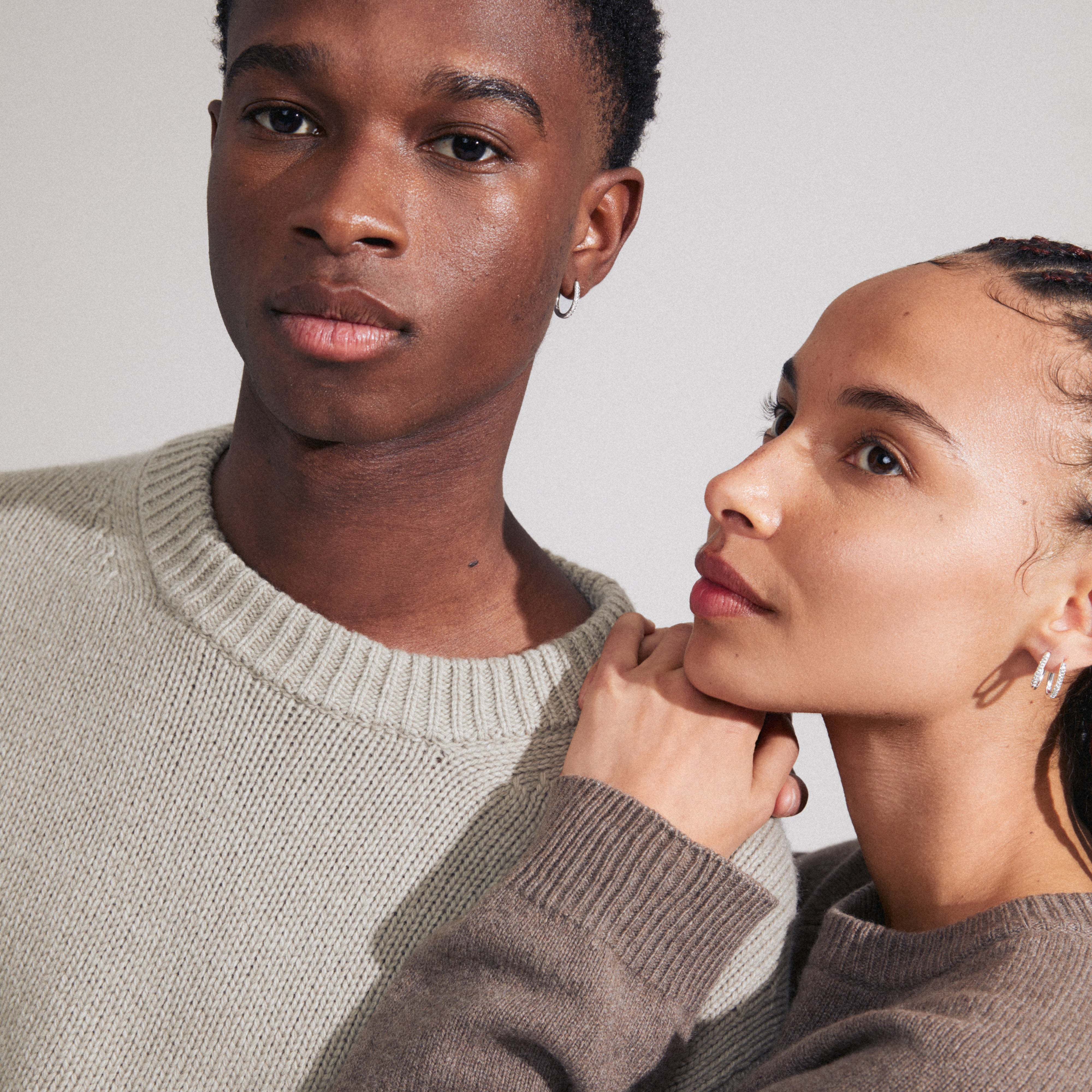 AMIRI silver-plated earrings with sparkling Preciosa crystals; a man and woman pose, highlighting the earrings' stylish elegance and easy click clasp.