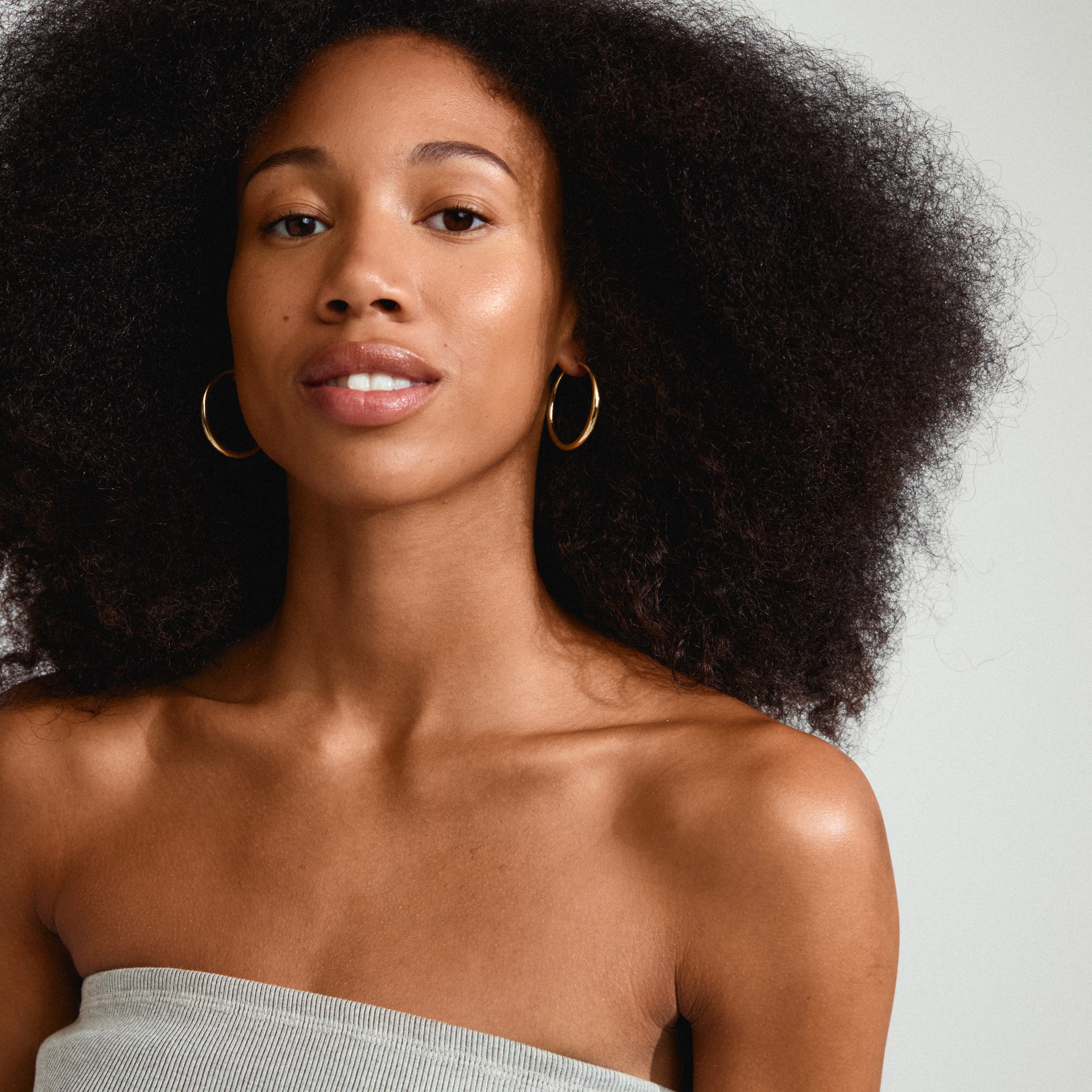 JORUN large hoop earrings gold-plated, showcased by a woman with afro hair, capturing the elegant simplicity and timeless style of these 40mm gold-plated essentials.
