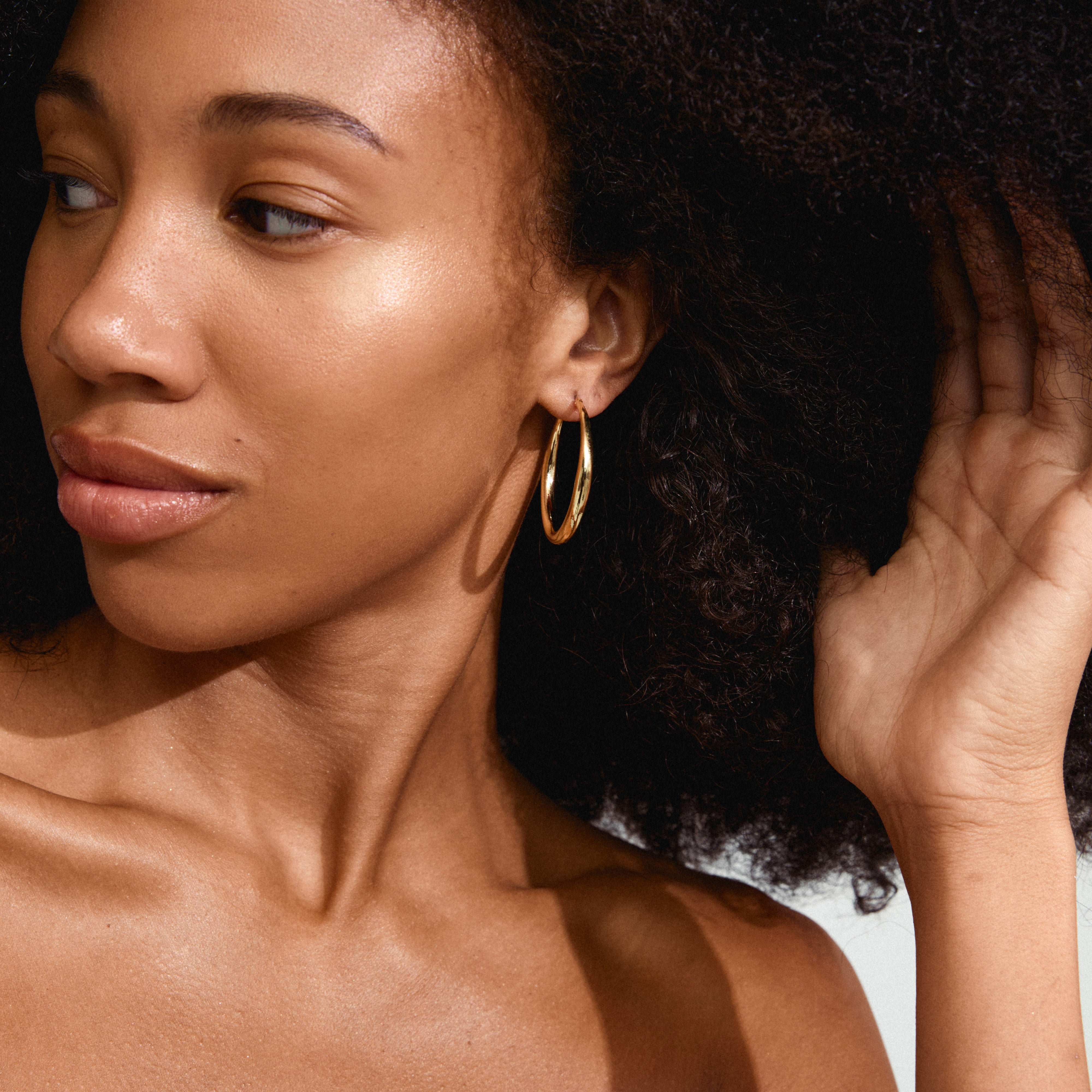 JORUN large hoop earrings, gold-plated, worn by a woman with curly hair and big earrings, highlighting their 40mm diameter and timeless design.
