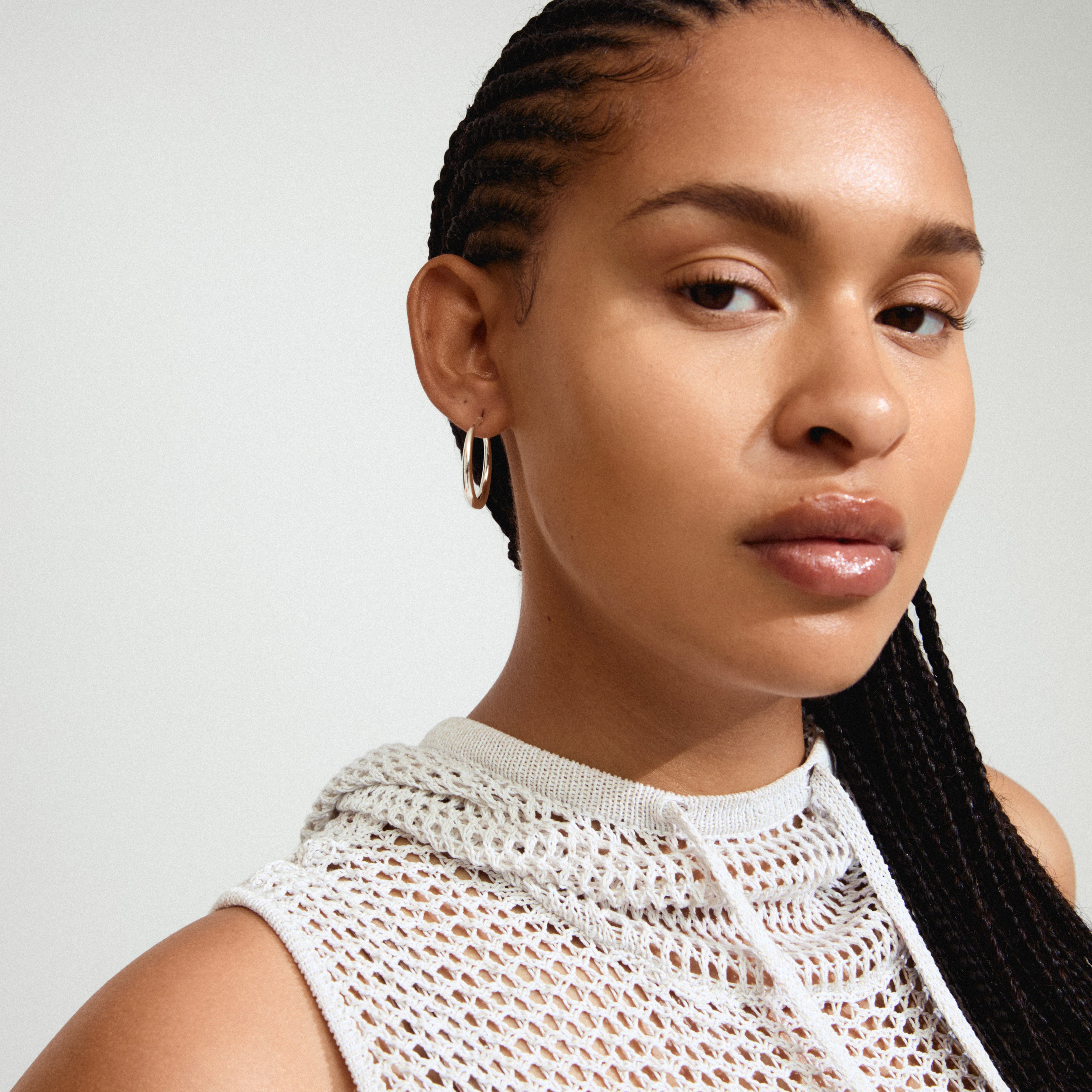 JORUN hoop earrings, silver-plated, showcased on a woman with braided hair. These 30mm timeless essentials effortlessly complement any style, perfect for versatile fashion statements.
