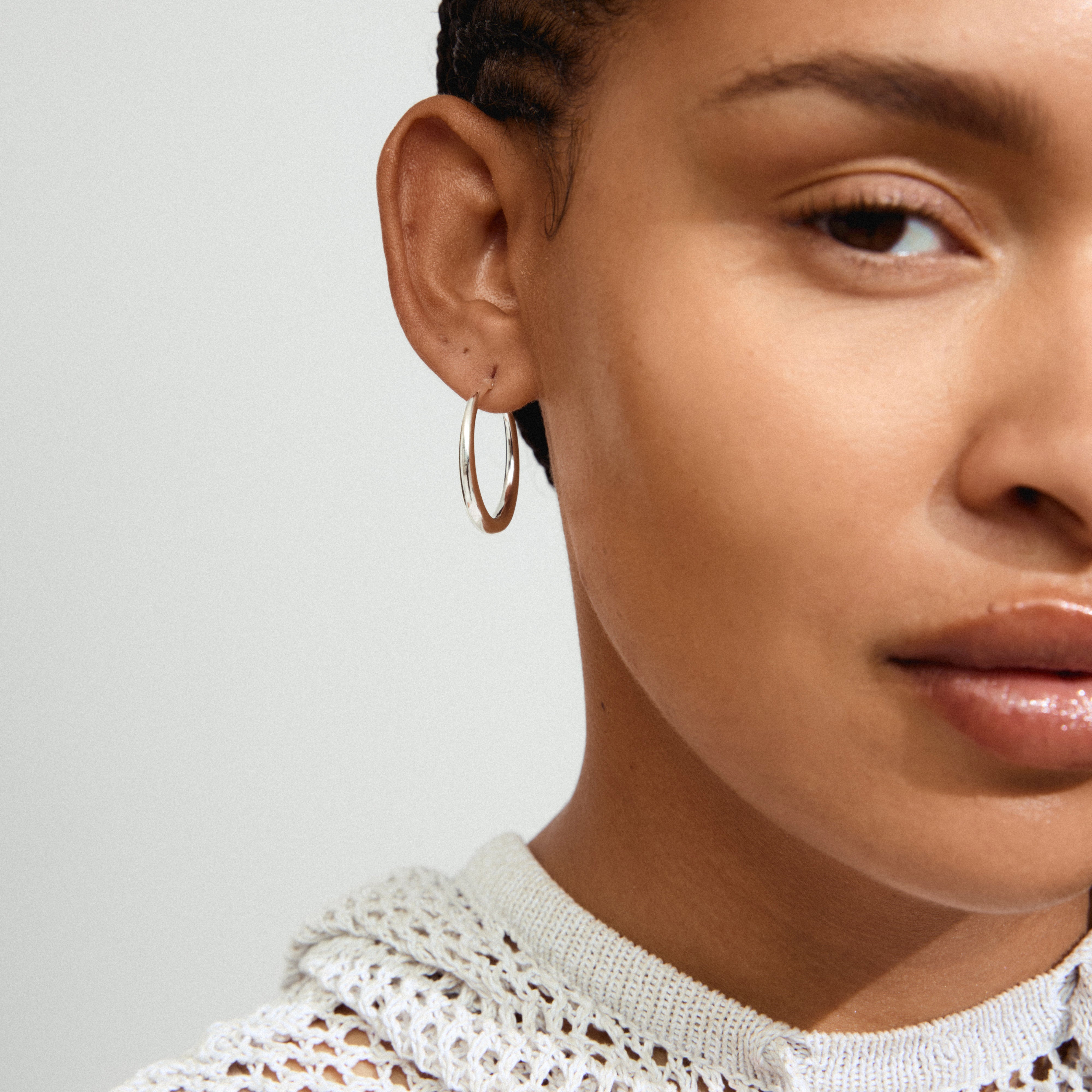 Close-up of a woman wearing JORUN silver-plated hoop earrings, highlighting their simple, elegant design and 30mm diameter.