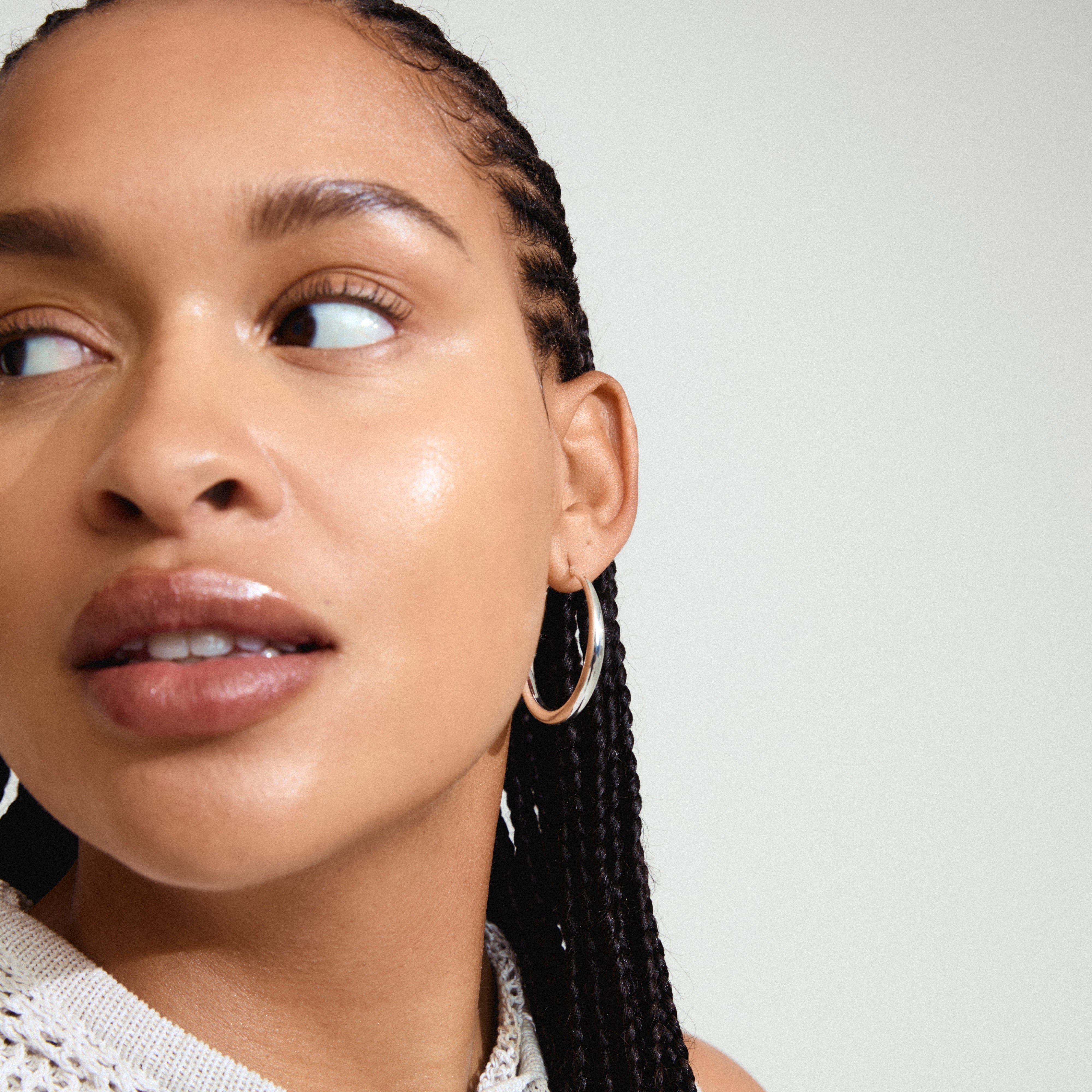 JORUN large hoop earrings, silver-plated, adorn a woman's ear, showcasing timeless elegance with a 40mm diameter, perfect for any wardrobe.