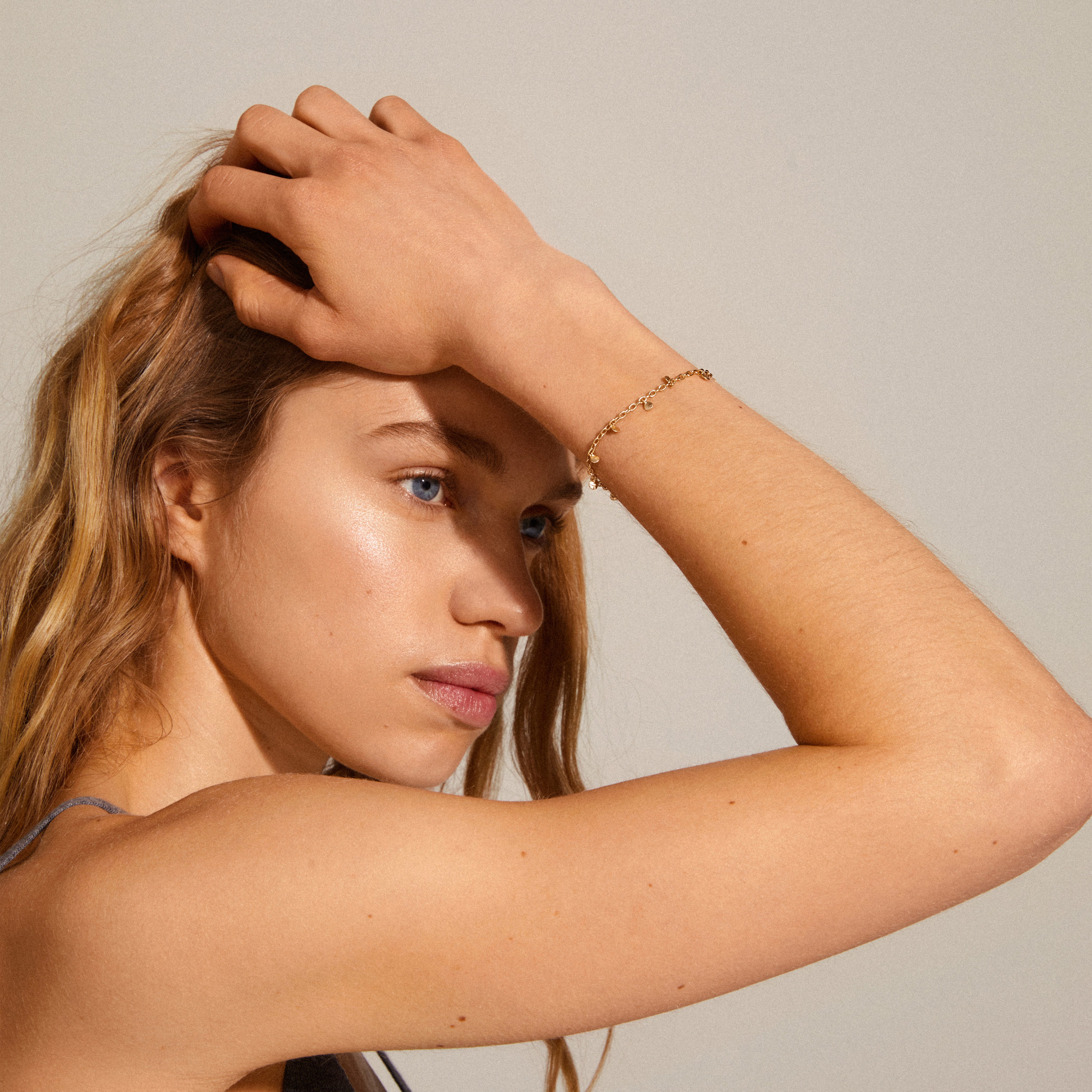 PANNA gold-plated coin bracelet on woman's wrist, featuring delicate chain design with small polished coins, exemplifying Pilgrim's blend of timeless and trendy Scandinavian style.