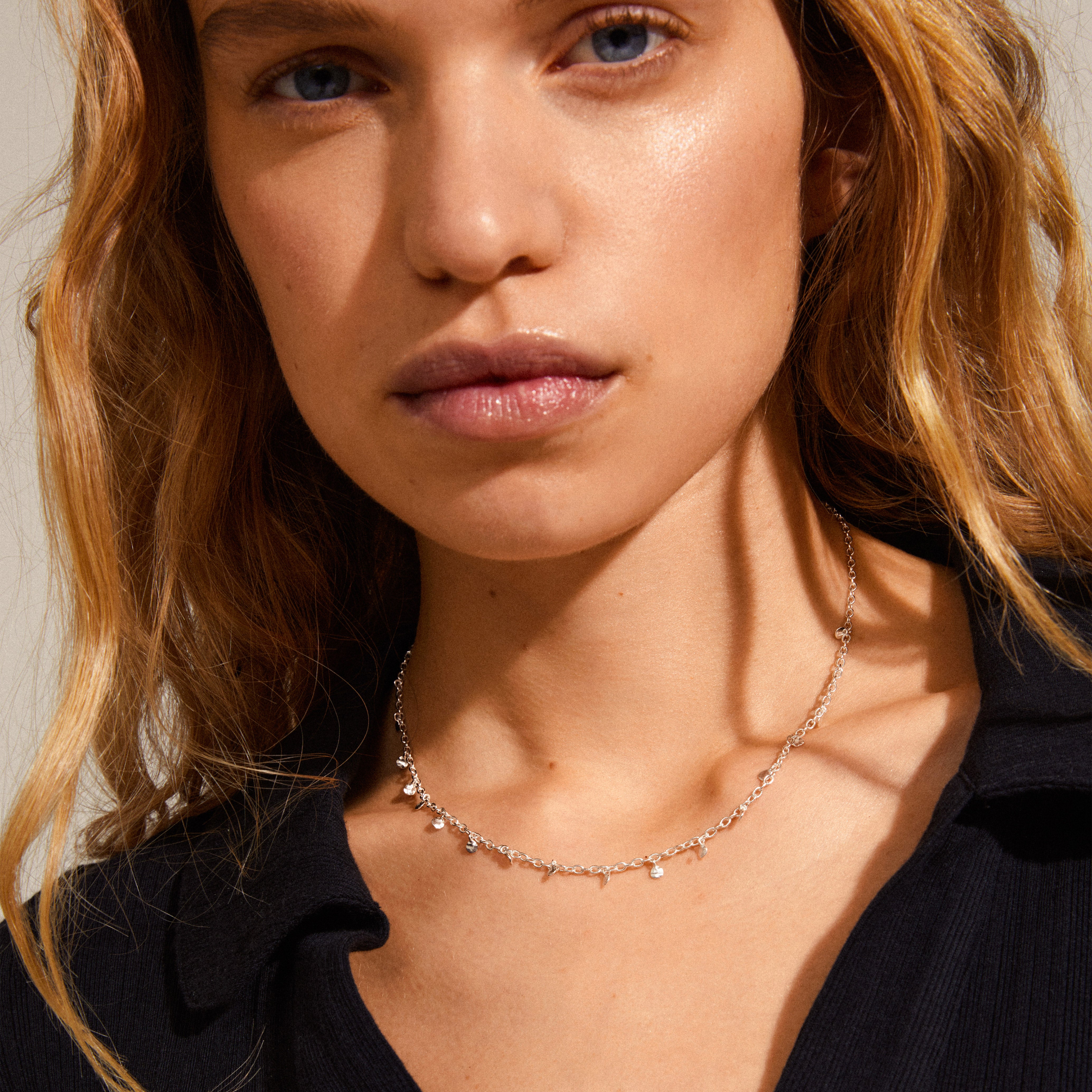 PANNA coin necklace silver-plated worn by a woman with blonde hair, showcasing the delicate chain with round polished pendants, complementing her edgy black shirt.