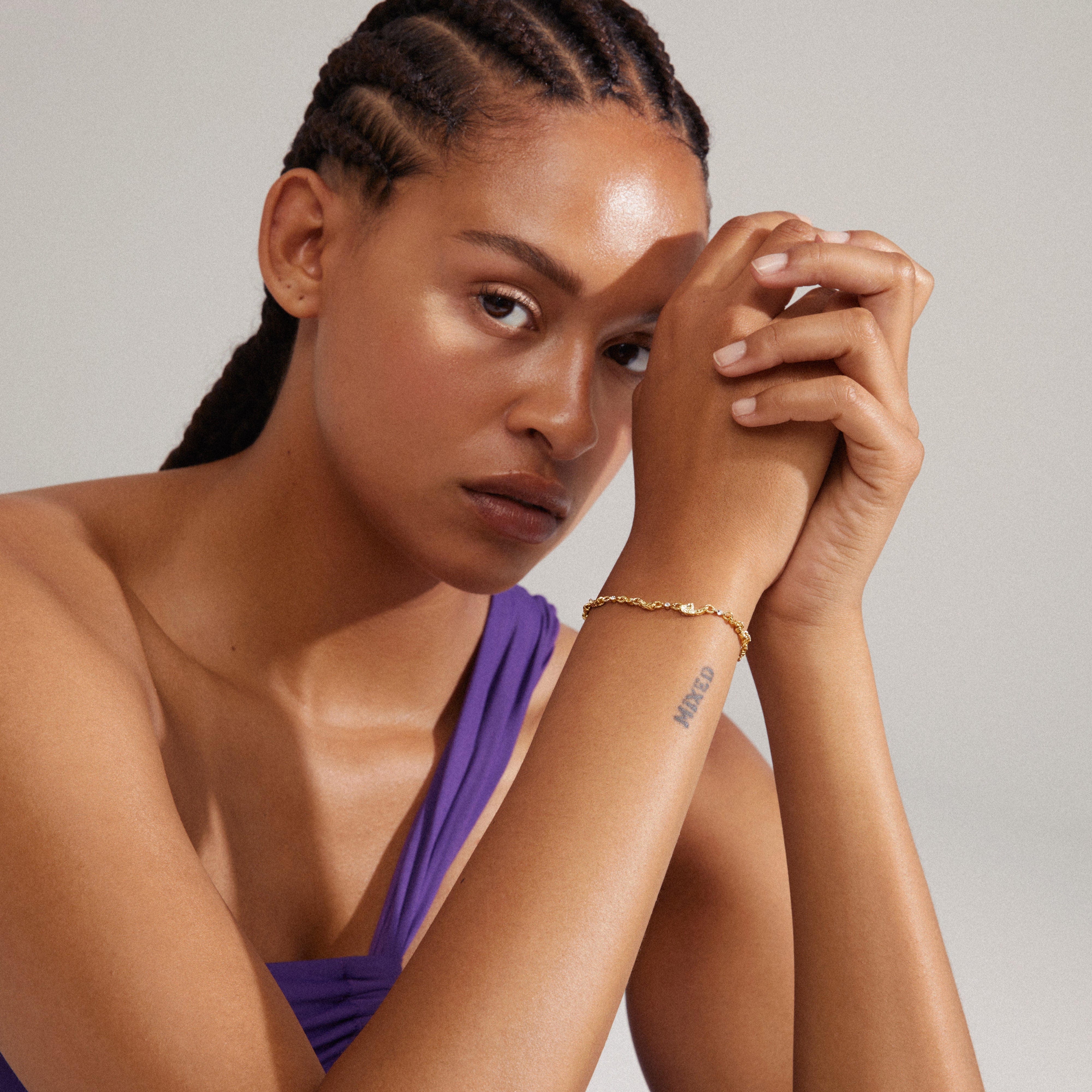Woman with braided hair wearing Pilgrim's HALLIE organic shaped crystal bracelet, gold-plated, showcasing its unique, asymmetric design and chic chain details.