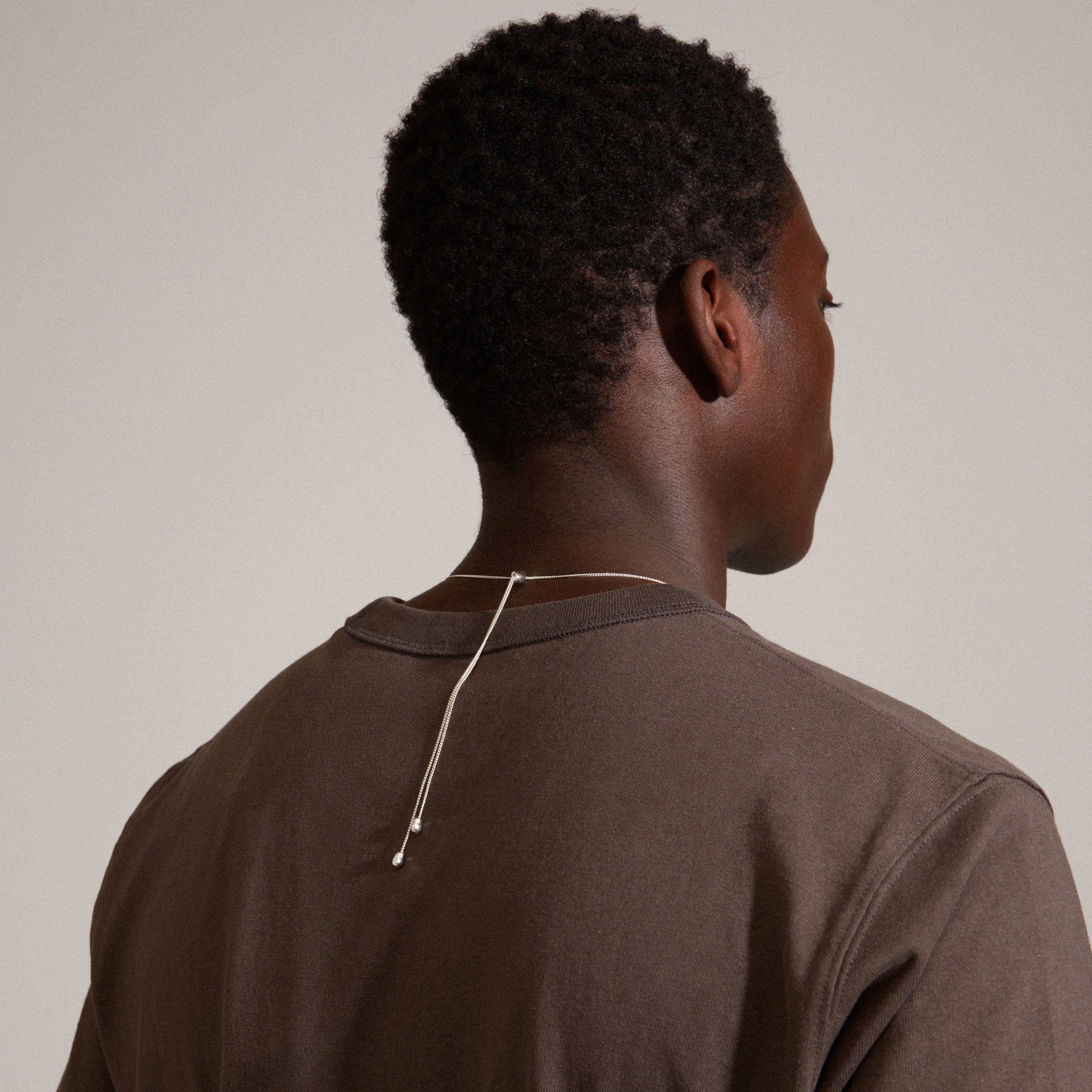 Man wearing Pilgrim's CHANTAL pendant necklace, silver-plated with an organic-shaped pendant on a slim, adjustable chain, showcasing its handcrafted elegance.