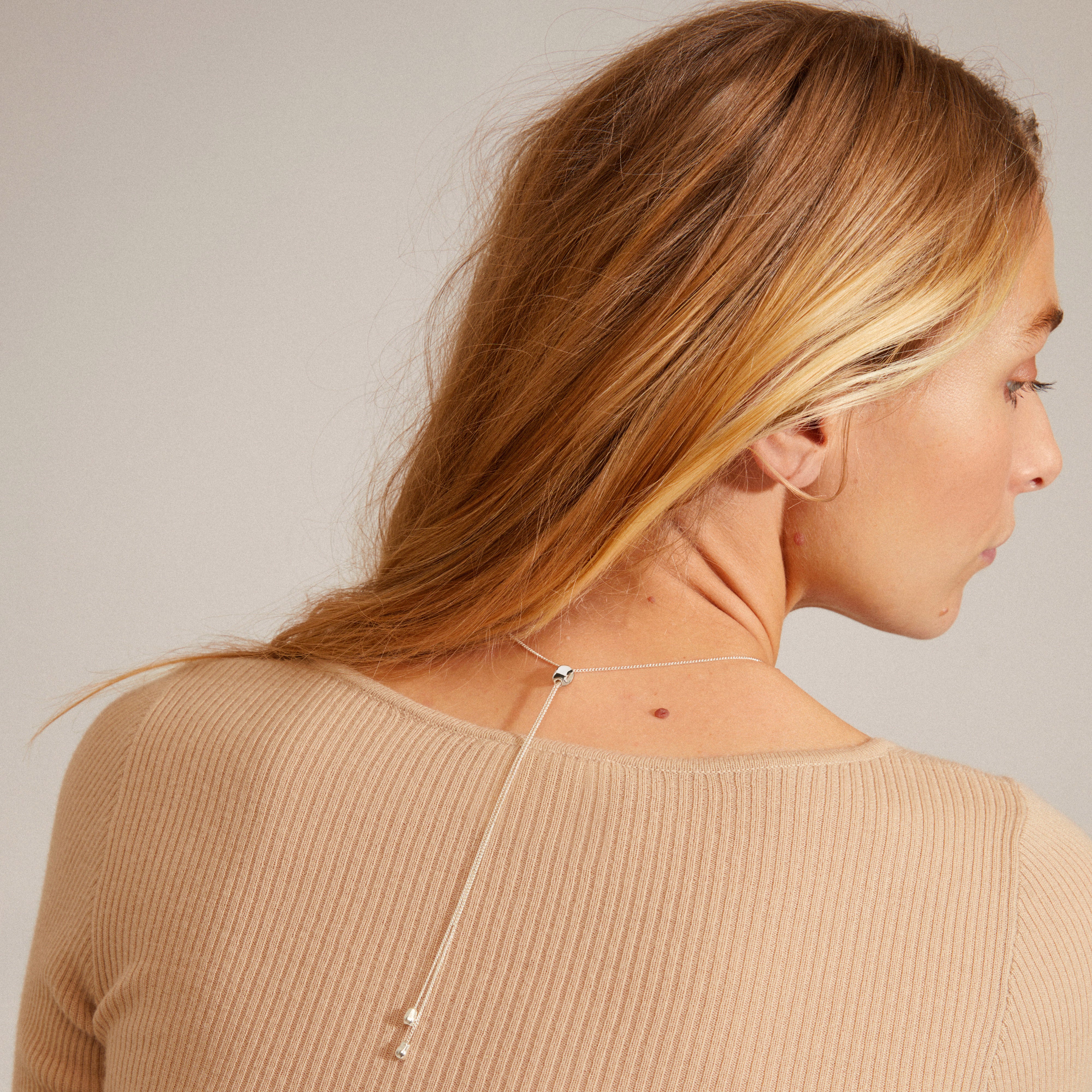 CHANTAL pendant necklace silver-plated, worn by a woman, features an adjustable slim chain and shiny organic-shaped pendant, embodying Pilgrim's handcrafted, timeless Danish design.