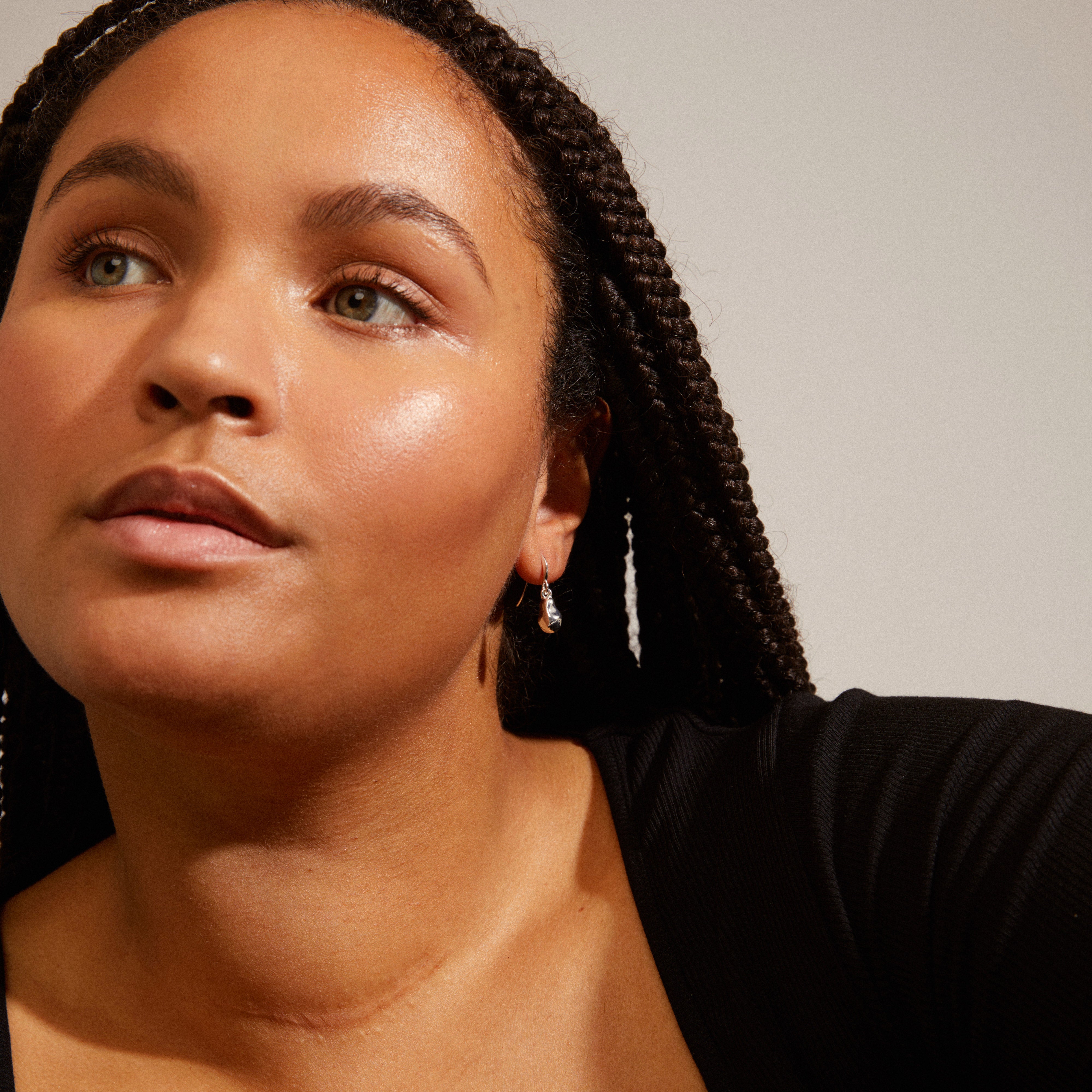 Woman with braided hair wearing CHANTAL silver-plated earrings from Pilgrim, showcasing shiny, light-reflecting surfaces and organic structure, enhancing winter fashion.