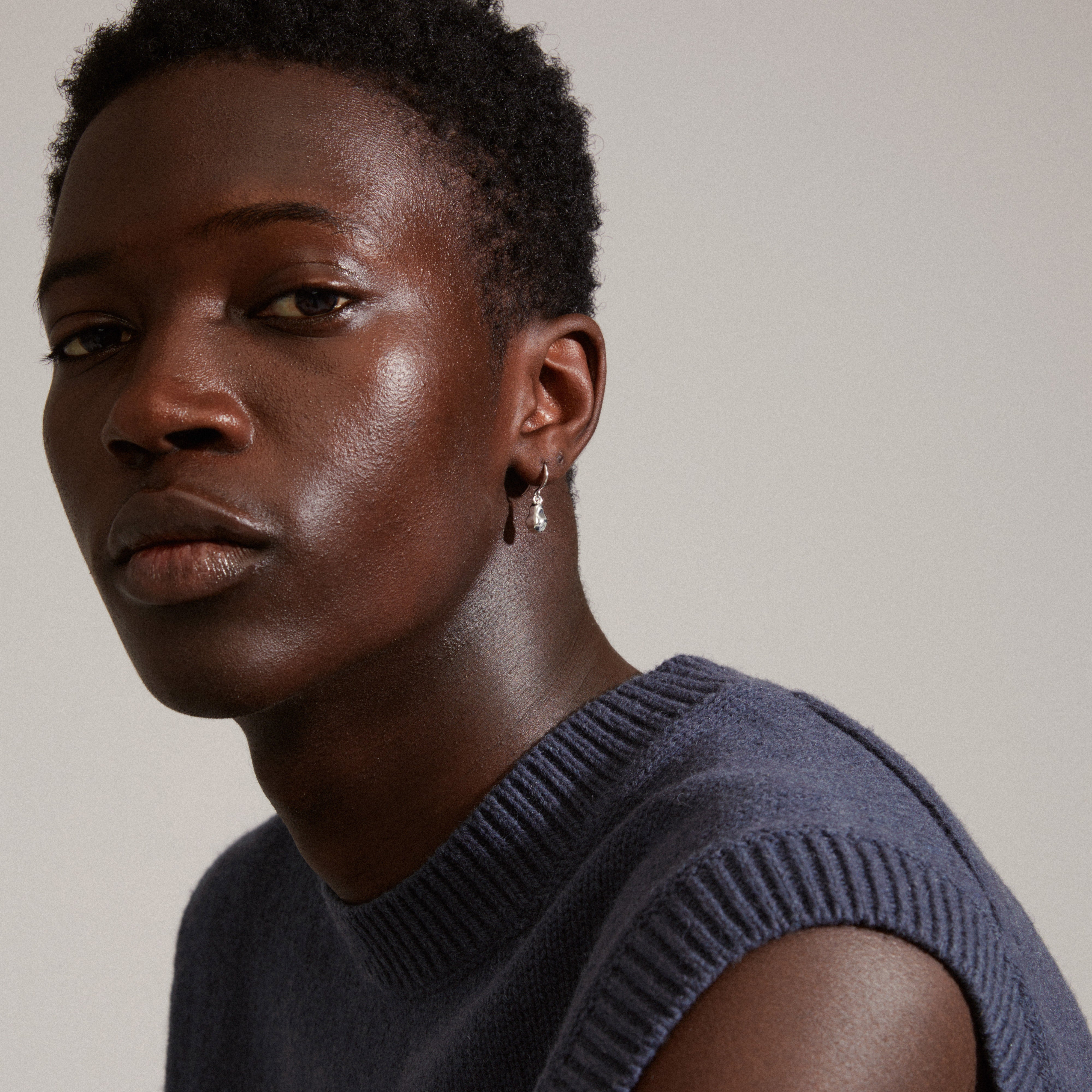 Close-up of a man wearing Pilgrim's CHANTAL silver-plated earrings, showcasing their shiny, organic structure designed for a stylish, cozy winter look.