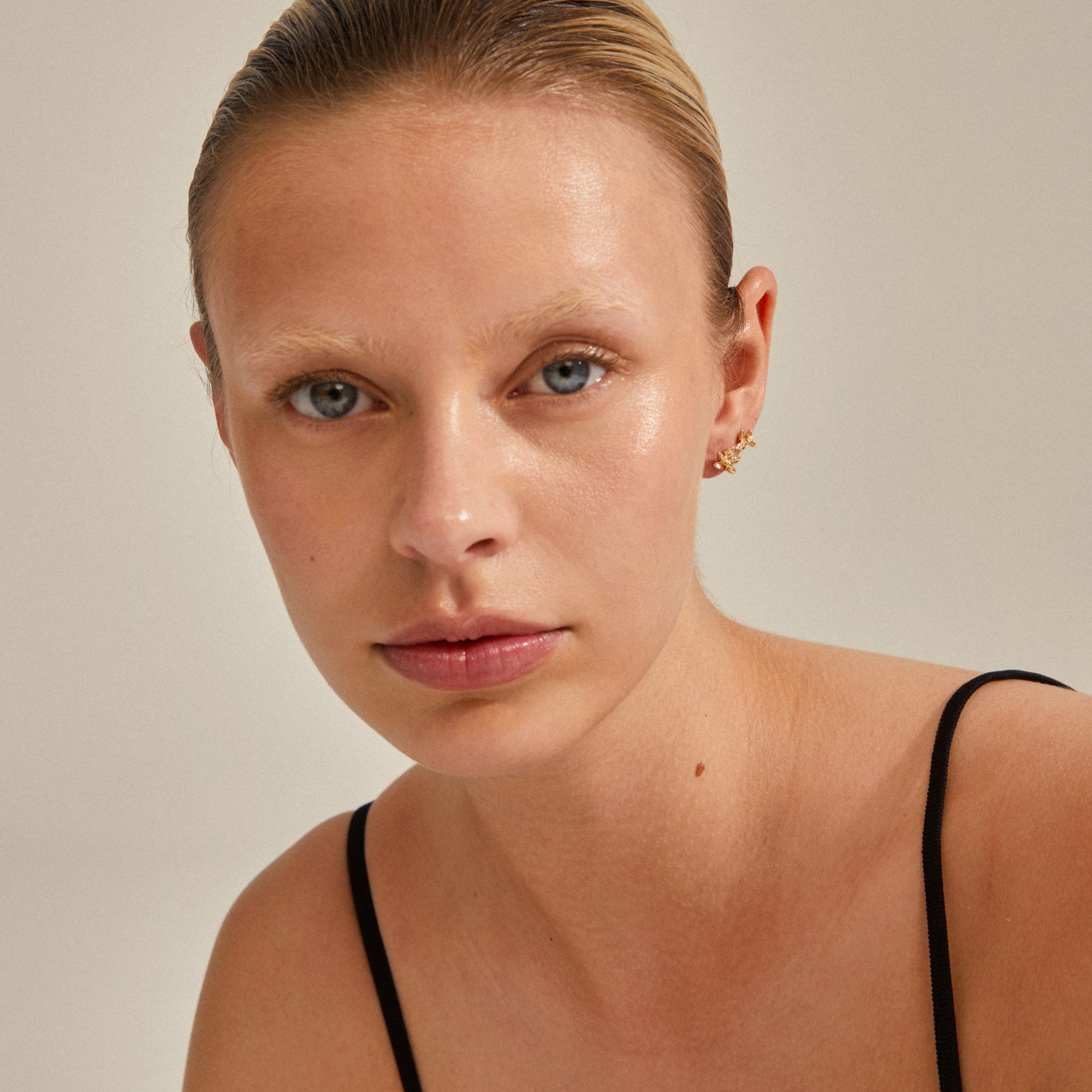 RIKO earrings, 2-in-1 set, gold-plated, displayed on a woman, showcasing their unique, nature-inspired shapes as she gazes at the camera.