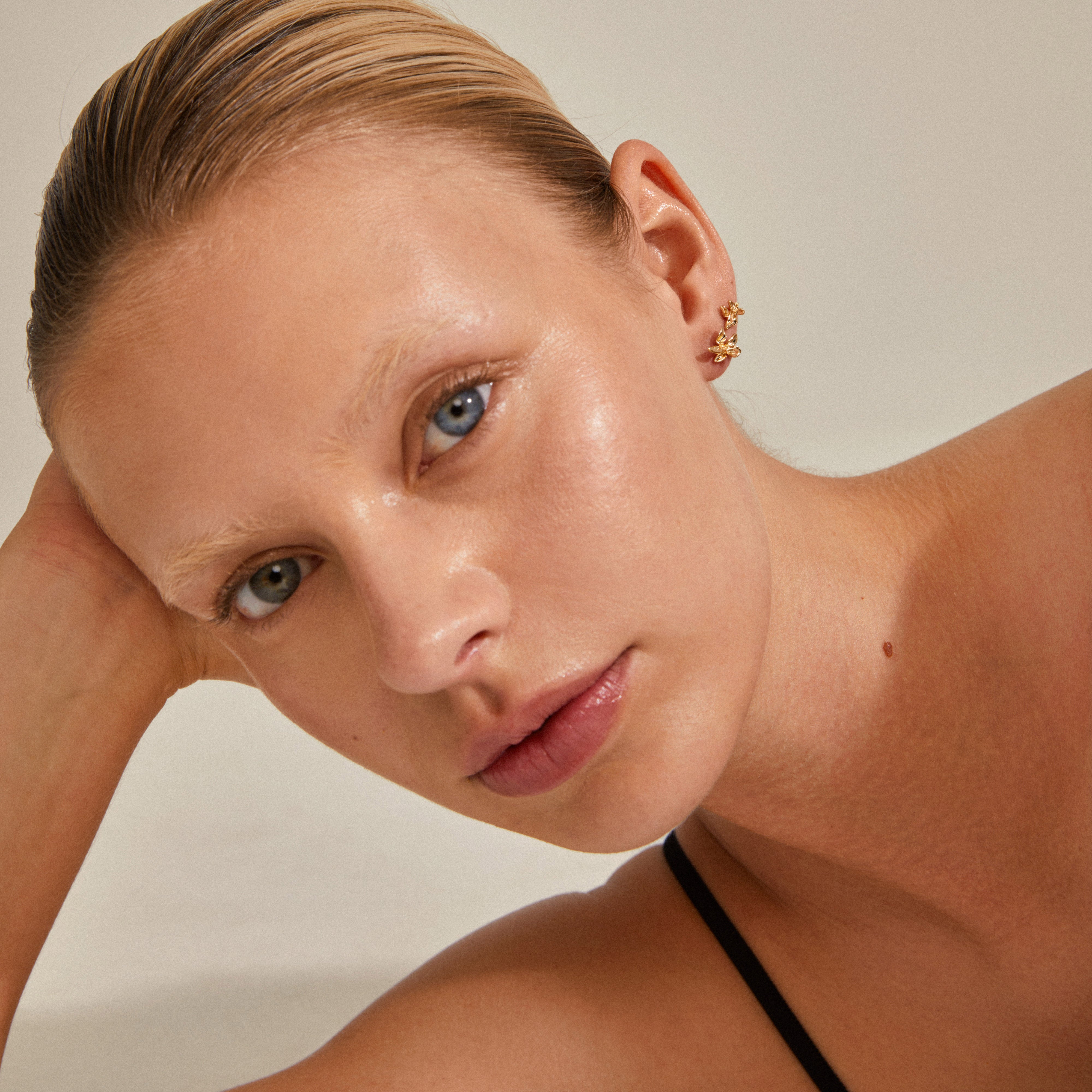 RIKO earrings, 2-in-1 set, gold-plated, featuring organic shapes inspired by nature, beautifully worn by a woman with blonde hair and blue eyes.