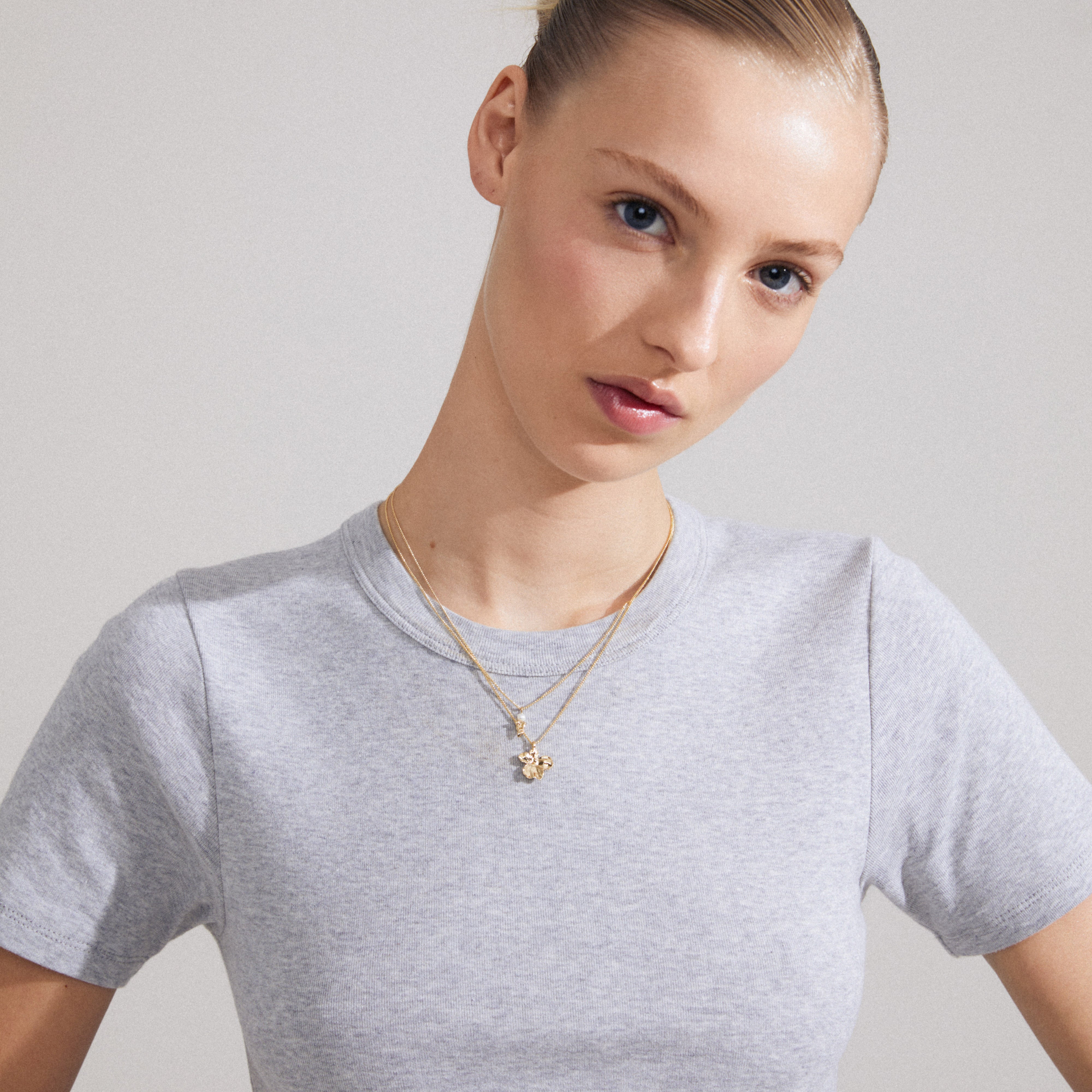 Close-up of a woman wearing the ZHURI necklace 2-in-1 set, featuring a gold-plated flower pendant and pearl, exemplifying Pilgrim's stylish, handmade jewelry.