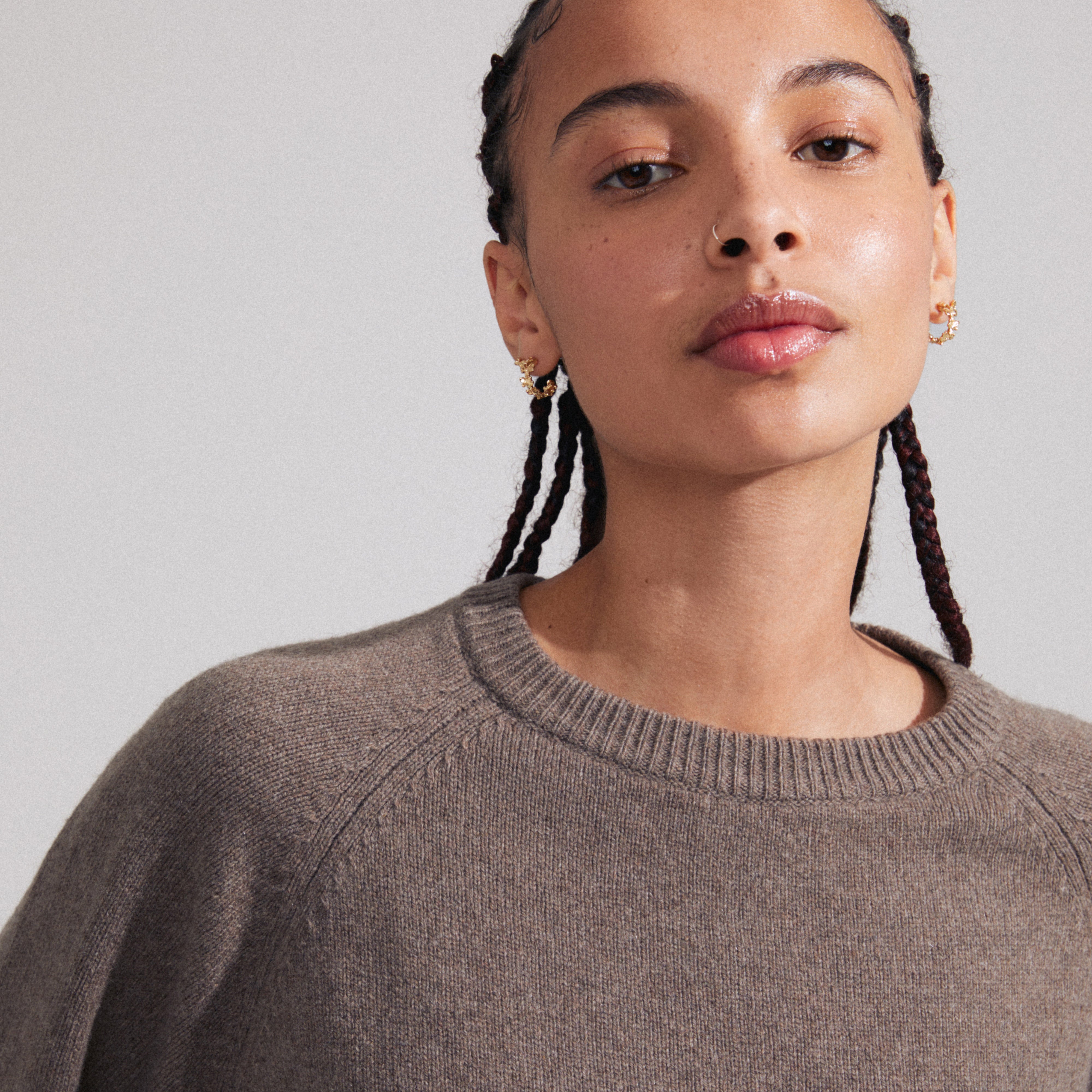 ZHURI earrings 2-in-1 set gold-plated, worn by a woman with braids, featuring floral half-hoops and studs from Pilgrim's sustainable collection.