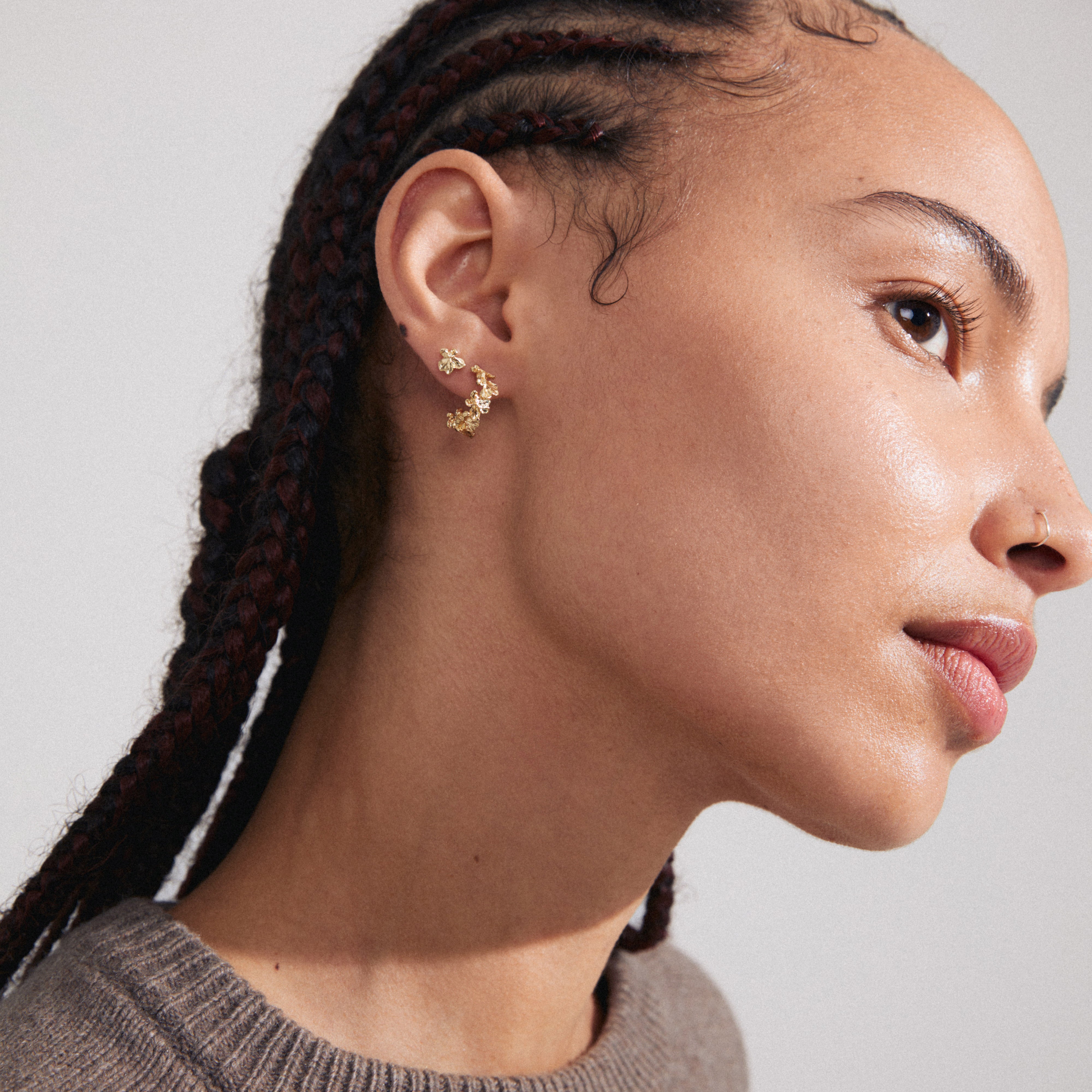 ZHURI earrings 2-in-1 set gold-plated, showcasing floral half-hoops and studs on a woman with braids, highlighting Pilgrim's trendy, inclusive design.