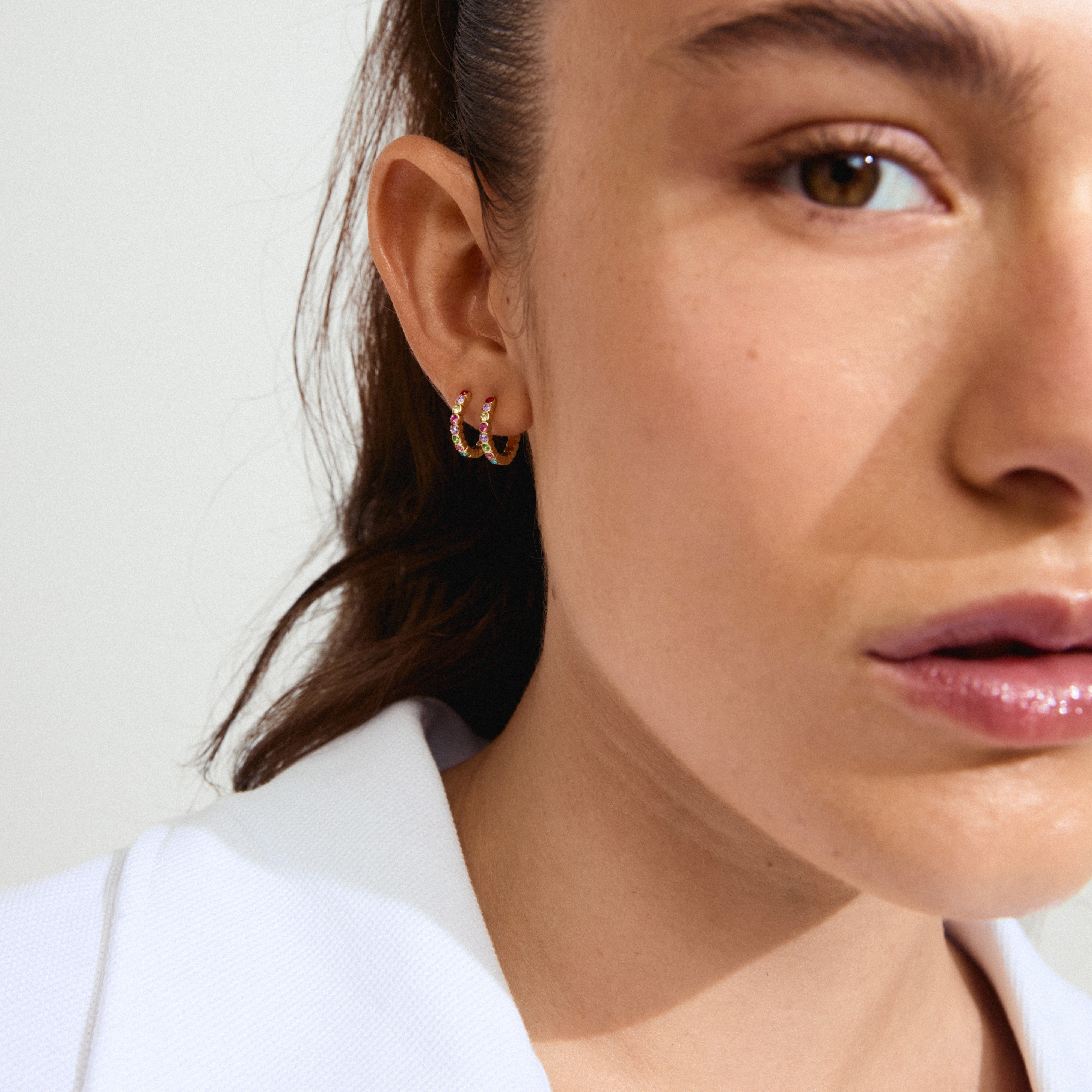 KLEOPRATRA hoop earrings gold-plated, featuring colorful Preciosa crystals and an easy click clasp, adorn a woman's ear, showcasing Pilgrim's handmade Danish jewelry.