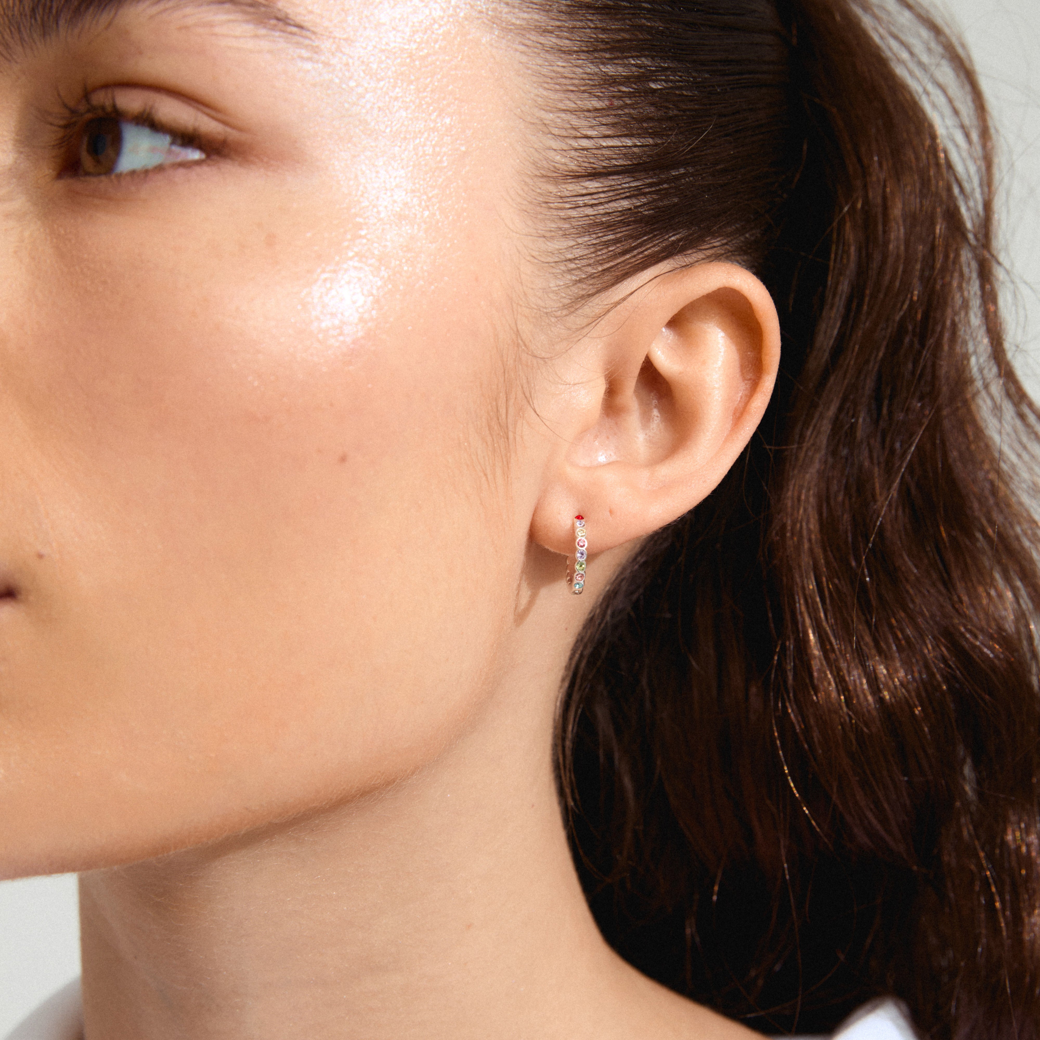 Close-up of a woman's face showcasing KLEOPRATRA silver-plated hoop earrings with colorful Preciosa crystals from Pilgrim. Ideal for adding sparkle to any look.