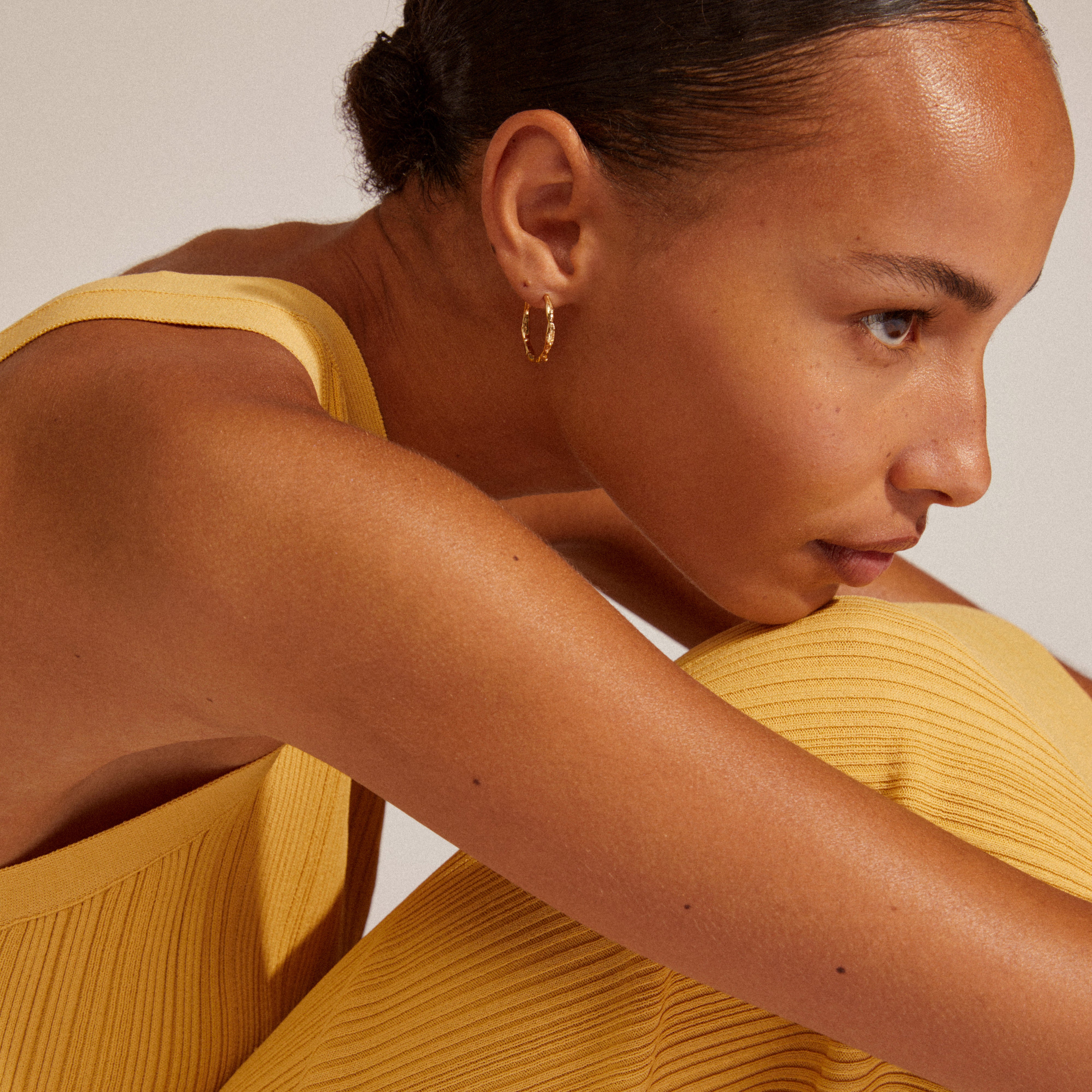 EDDY organic shaped large hoops gold-plated, displayed by a woman in a yellow dress, highlighting their handcrafted, unique design perfect for stylish adventures.