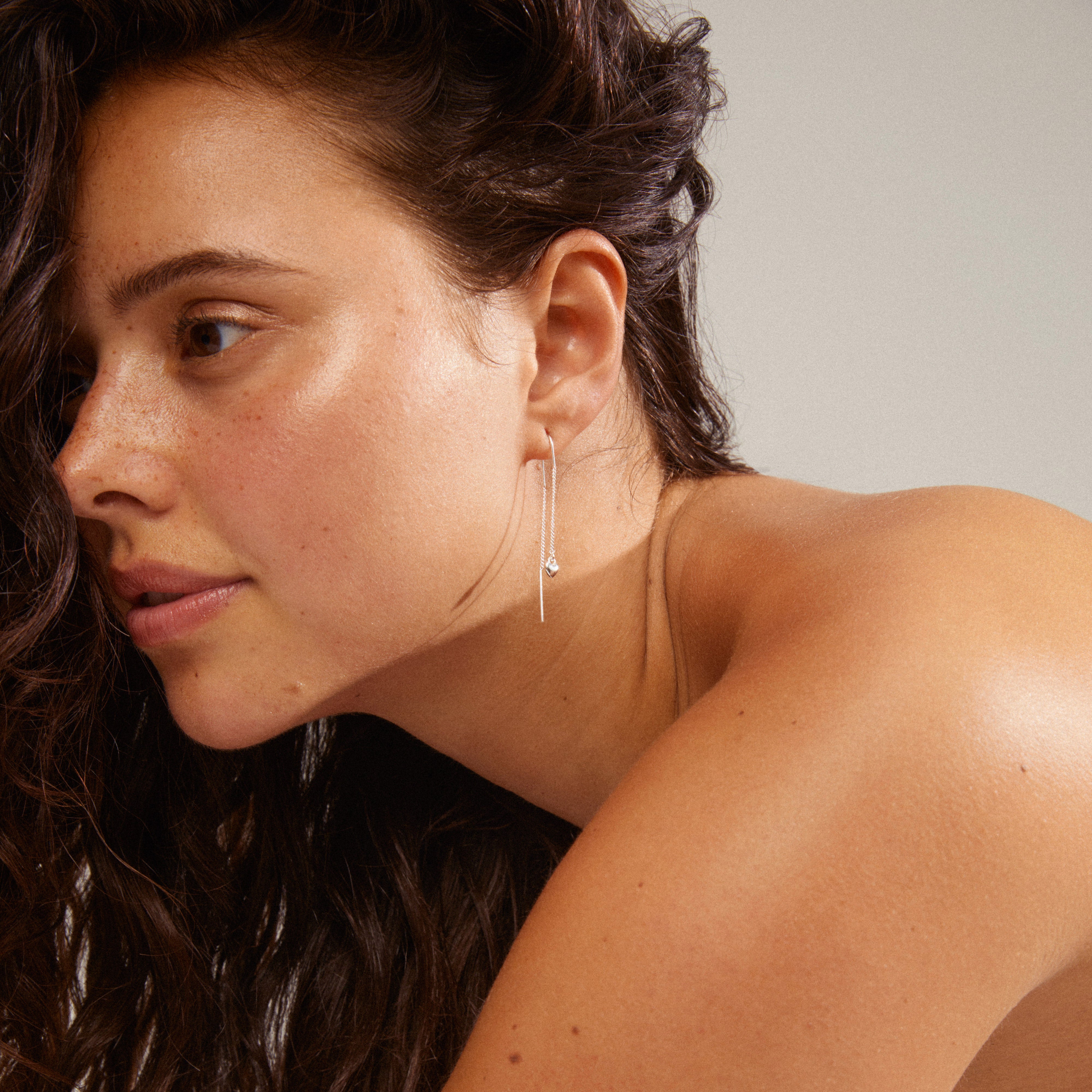 AFRODITTE heart chain-earrings silver-plated on a woman, showcasing their elegant, simple design, styled for a unique look.