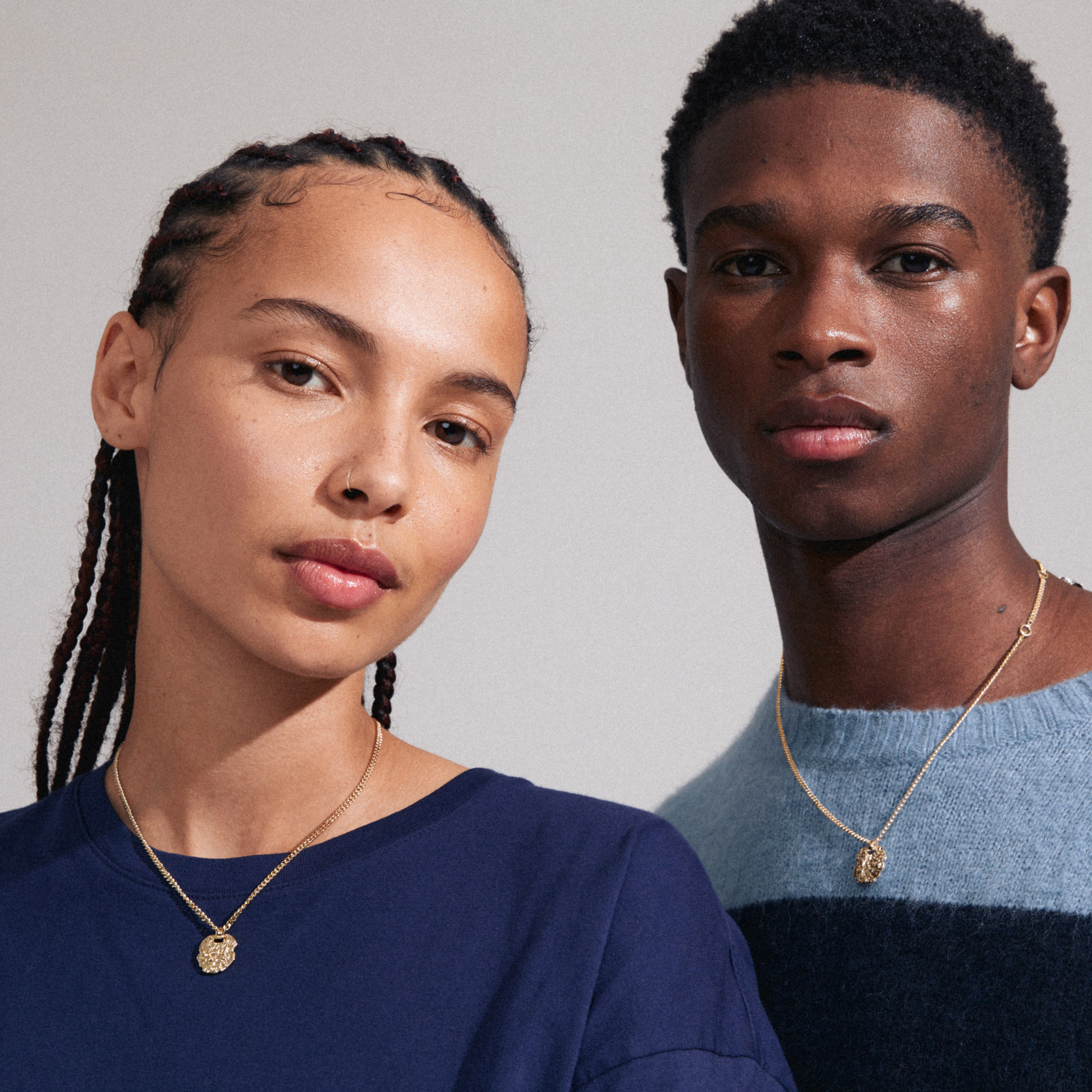 SCOTTIE coin necklace gold-plated on a woman with braids, showcasing a rustic coin pendant on a delicate chain, emphasizing genderless style and personal journey.