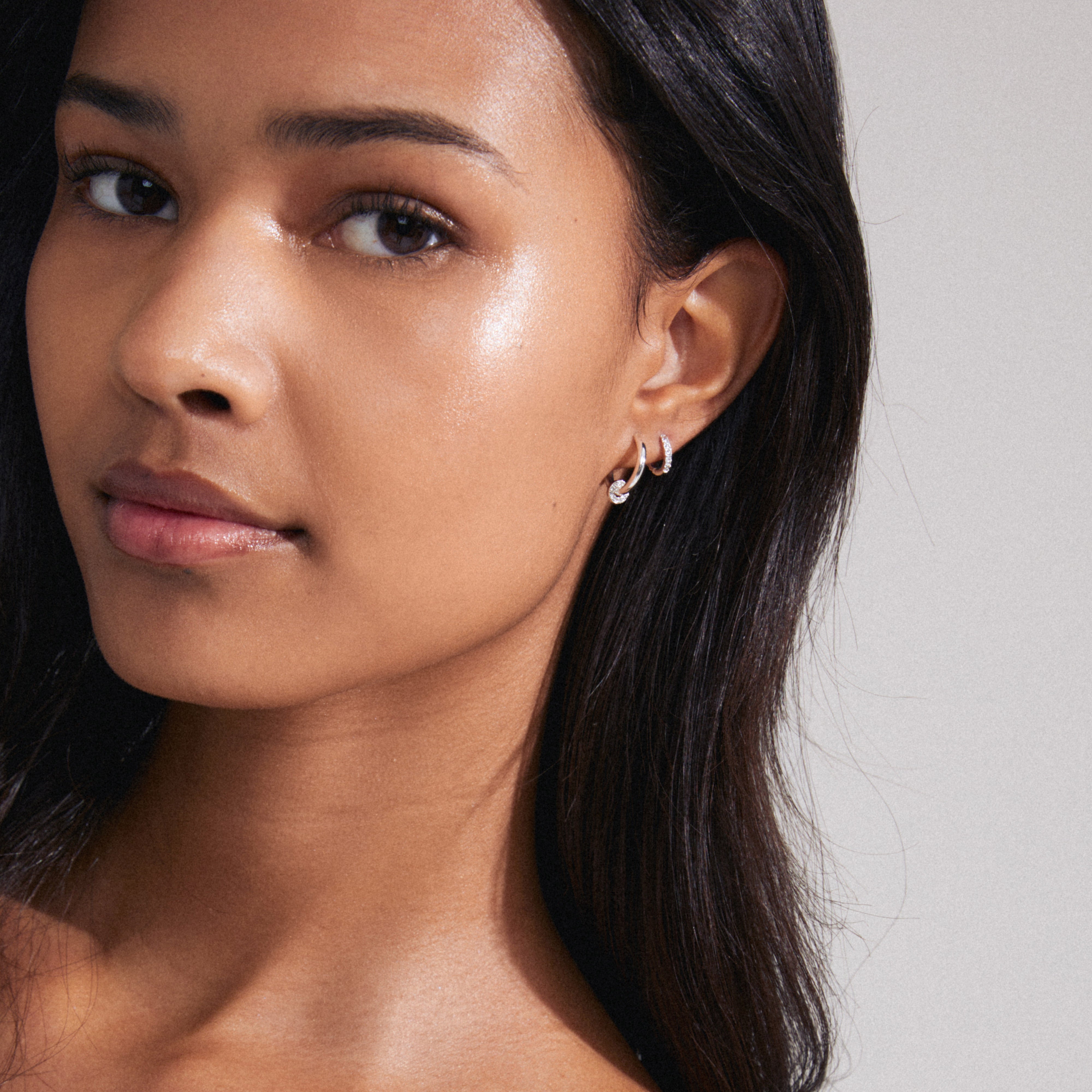 SCOTTIE earrings 2-in-1 set silver-plated: Close-up of a woman's ear showcasing silver-plated hoops, featuring sparkling crystals and a detachable pendant for versatile styling.