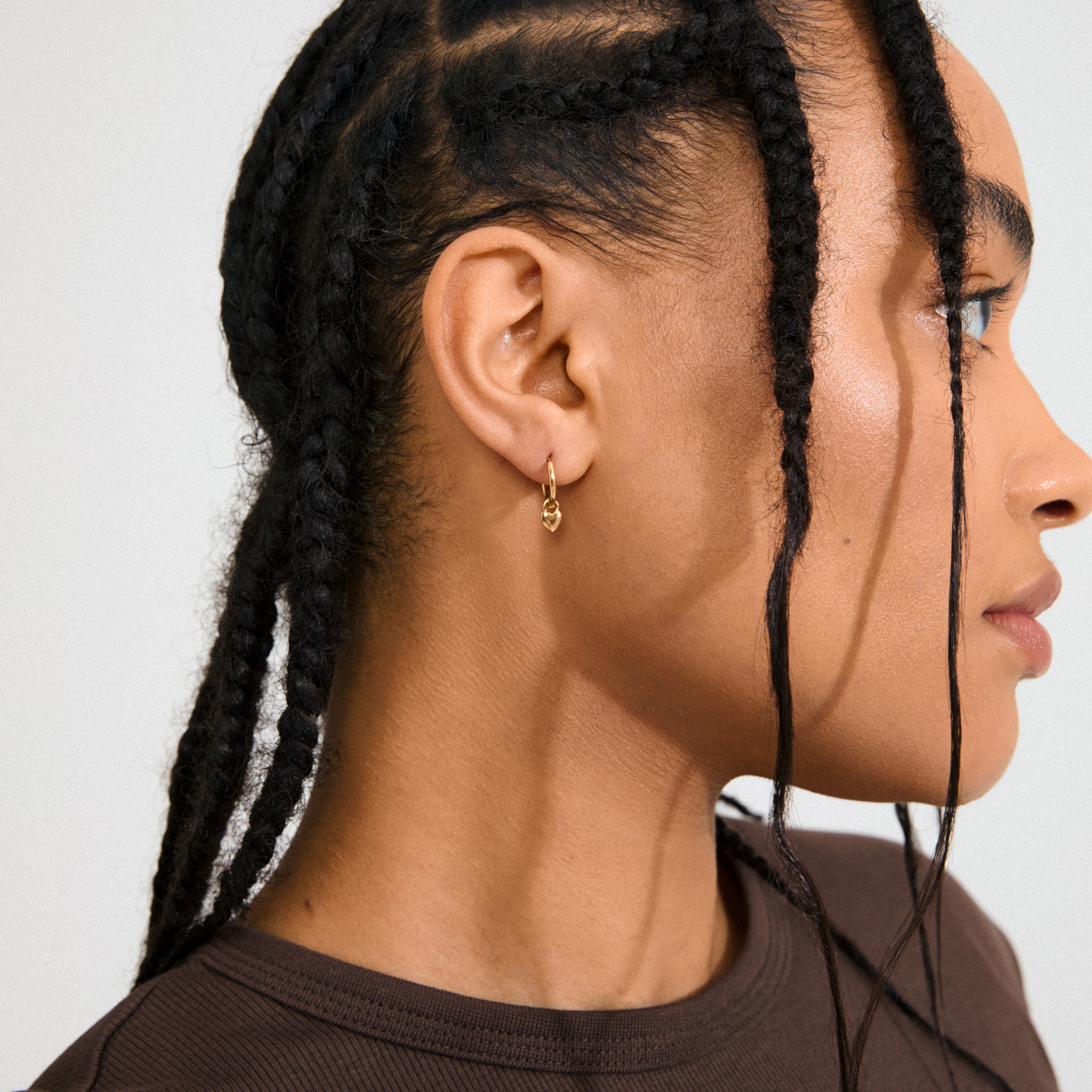 ALAIA earrings: Gold-plated huggie hoops with detachable heart pendants, offering a romantic yet modern style, perfect for everyday wear or special occasions.