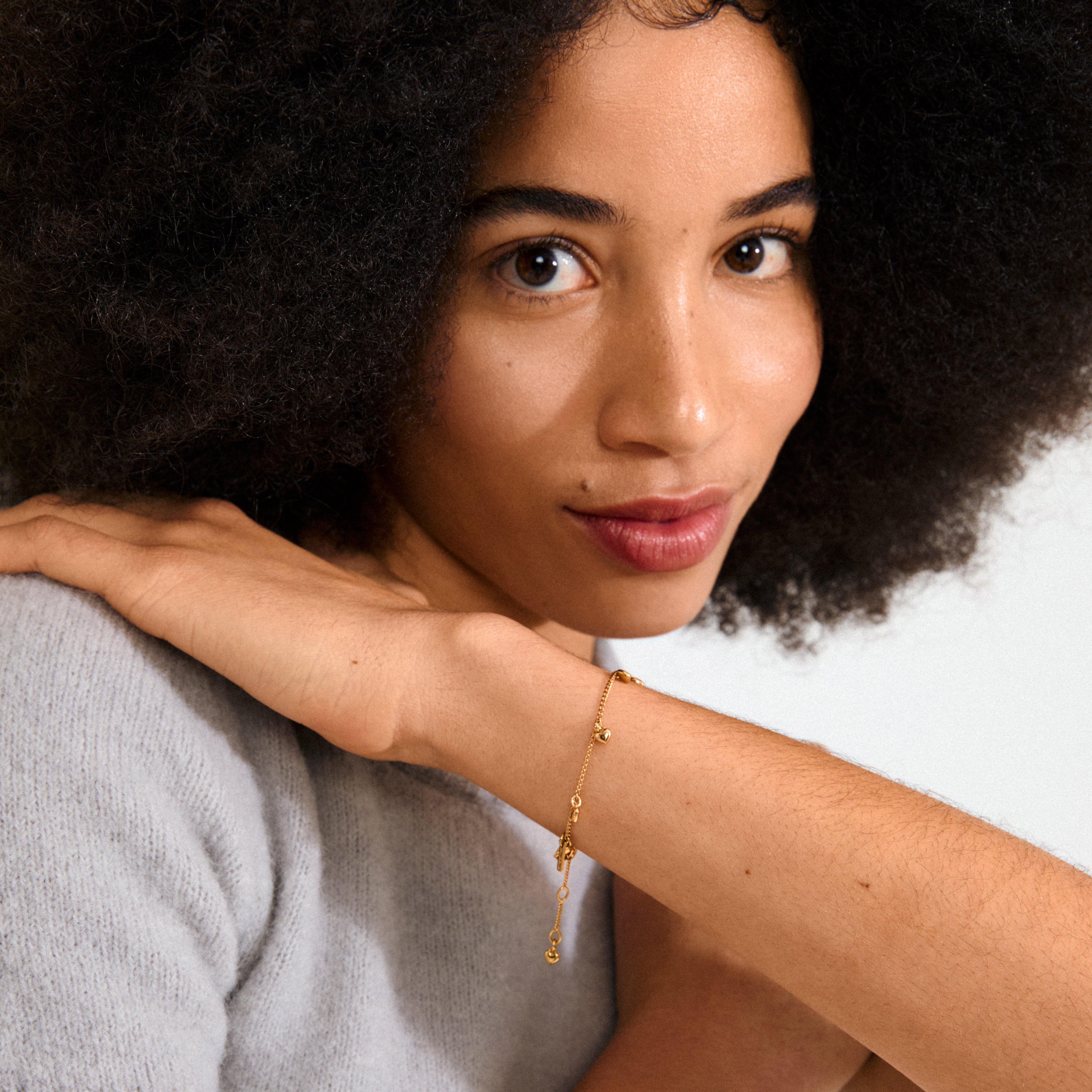 ALAIA gold-plated bracelet with eight tiny heart pendants on a slim curb chain, perfect for a romantic and playful accessory.