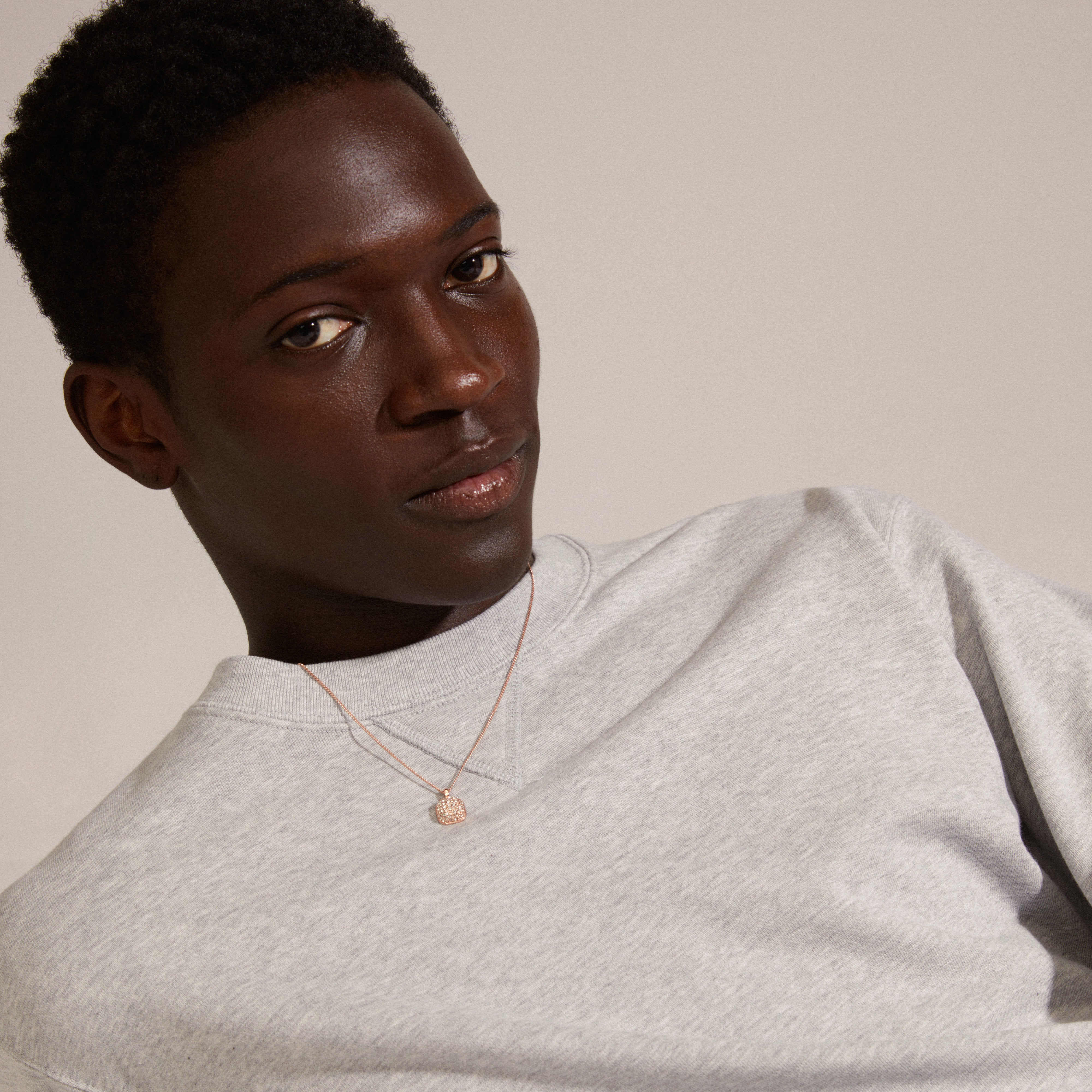 Man wearing the CINDY crystal pendant necklace, rose gold-plated, featuring a slim chain and square pendant with Preciosa crystals, from Pilgrim.