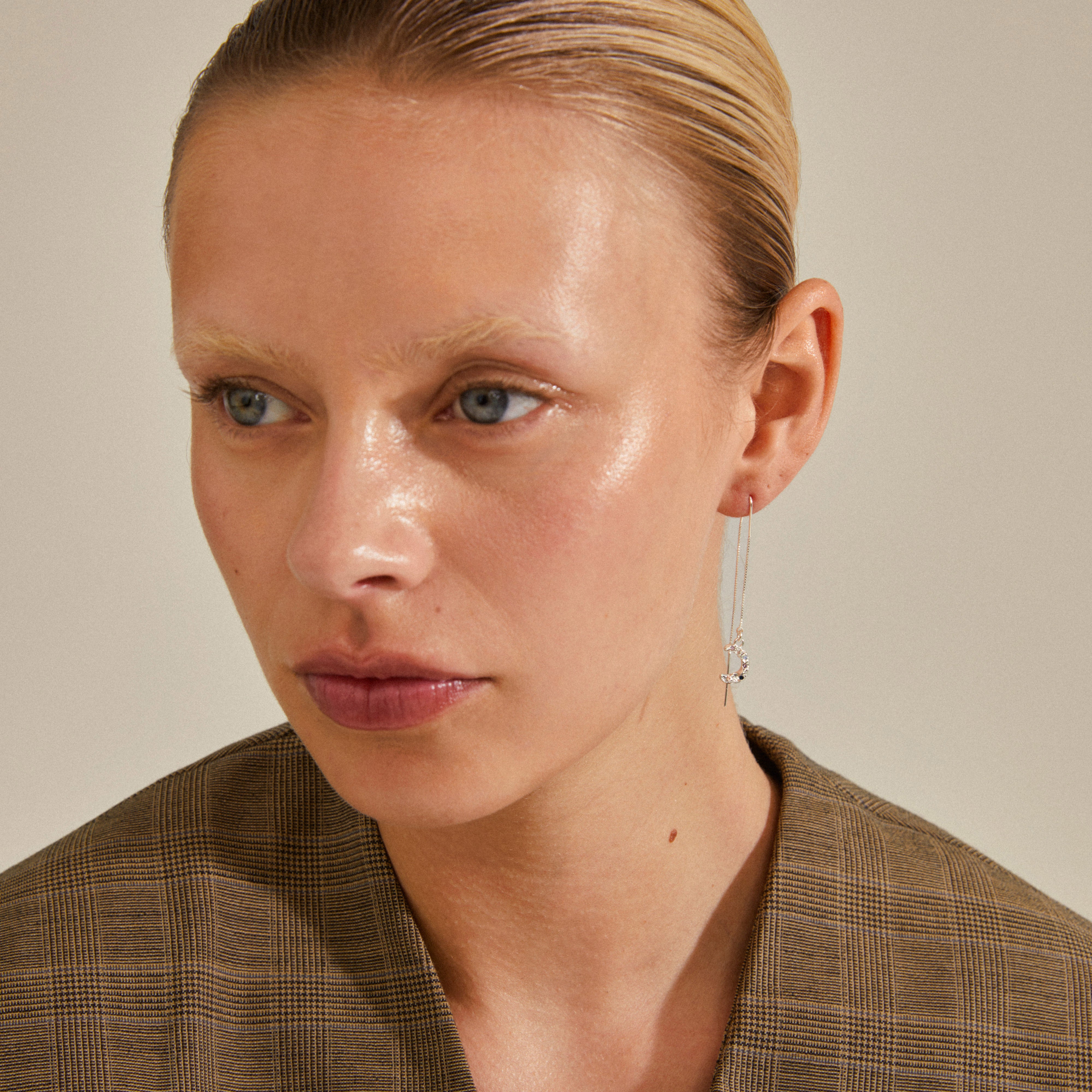 Woman wearing REMY chain earrings, silver-plated with a half moon pendant, showcasing their delicate, organically uneven design.