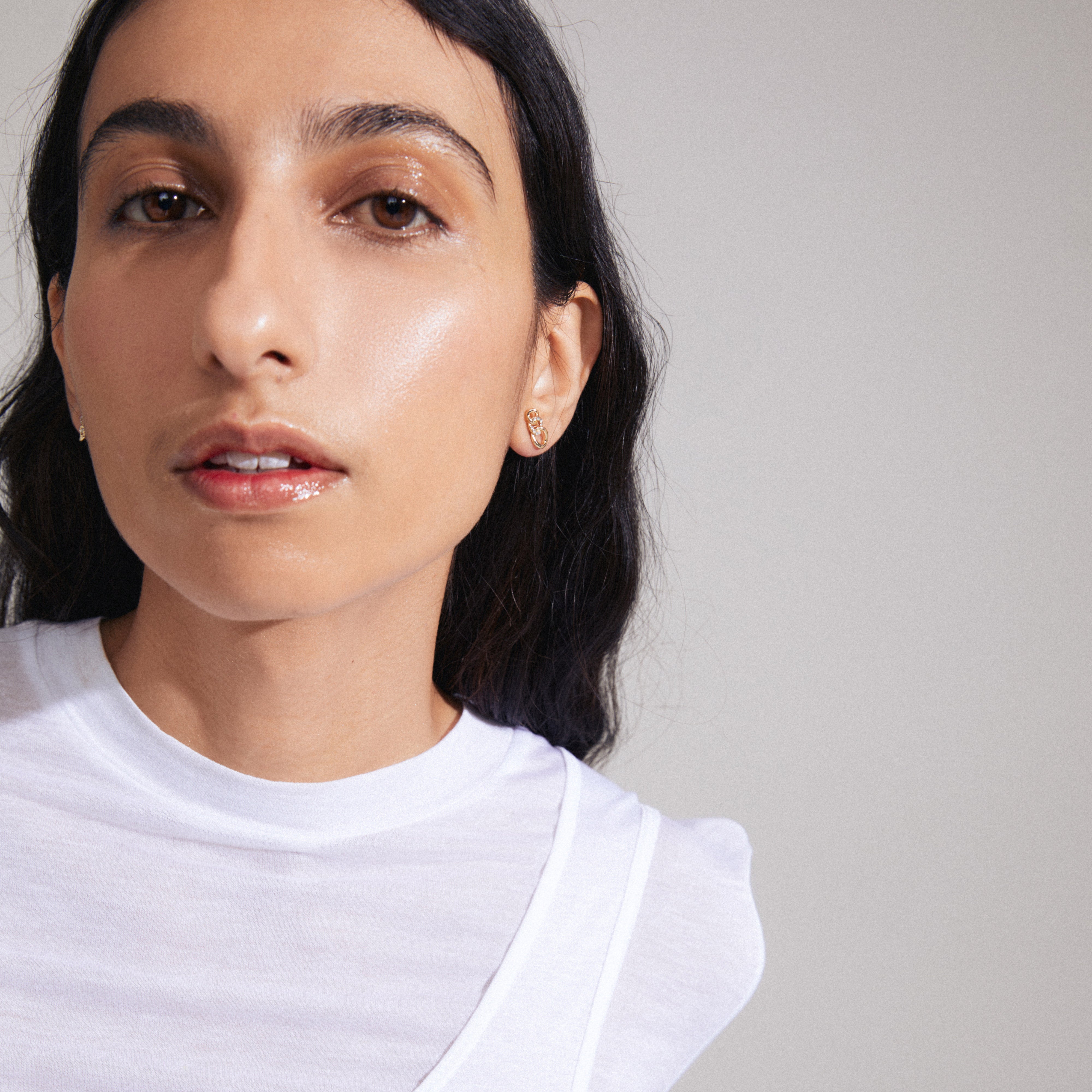 WRENLEY gold-plated earrings with flowing cable chains and sparkling Preciosa crystals, worn by a woman in a white shirt.