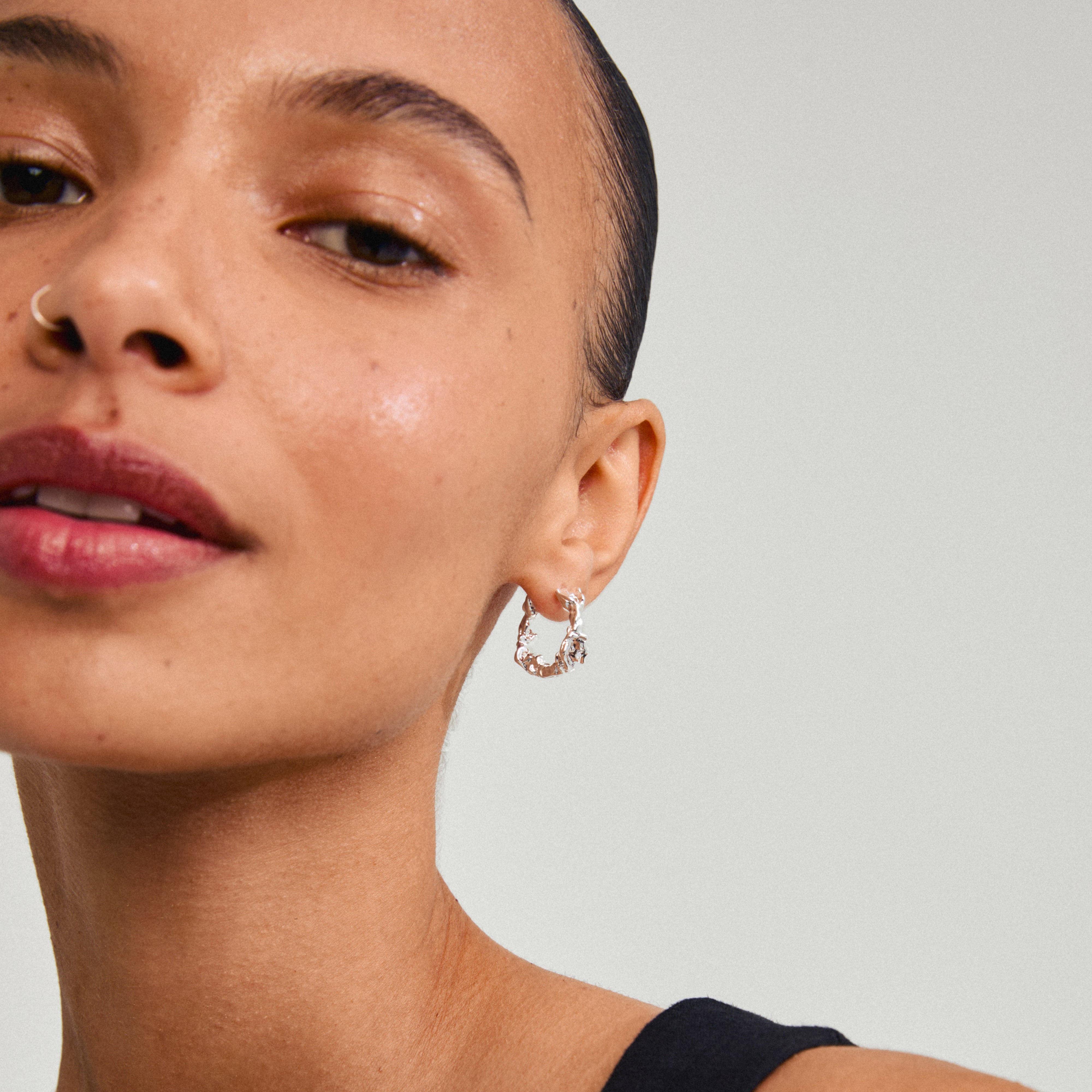 Close-up of a woman wearing Pilgrim's silver-plated TRUST earrings, showcasing their elegant, organic design, perfect for versatile styling and crafted from recycled materials.