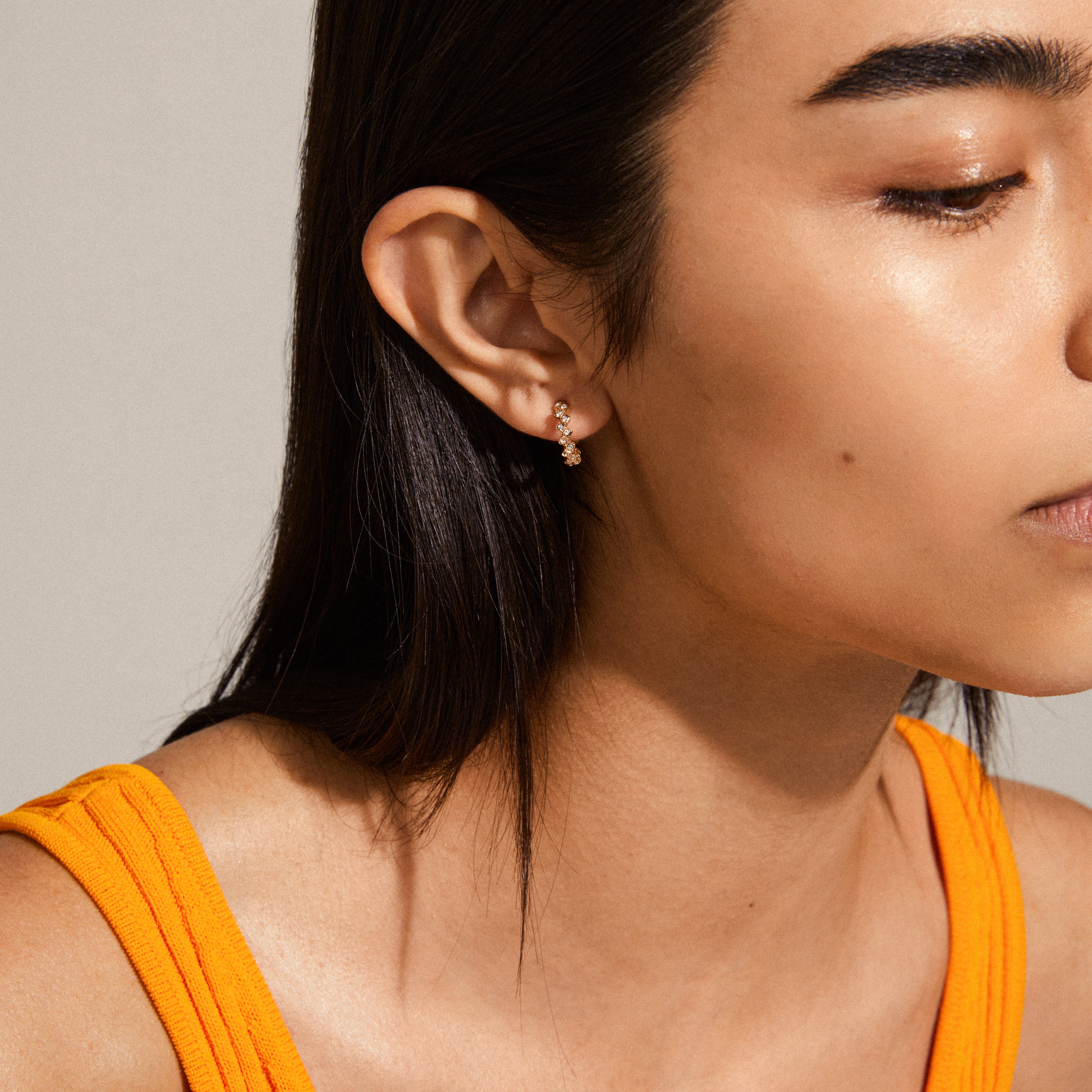 ESTER crystal hoop earrings, gold-plated, worn by a woman with dark hair, showcasing their angular design and sparkling Preciosa crystals for an elegant touch.
