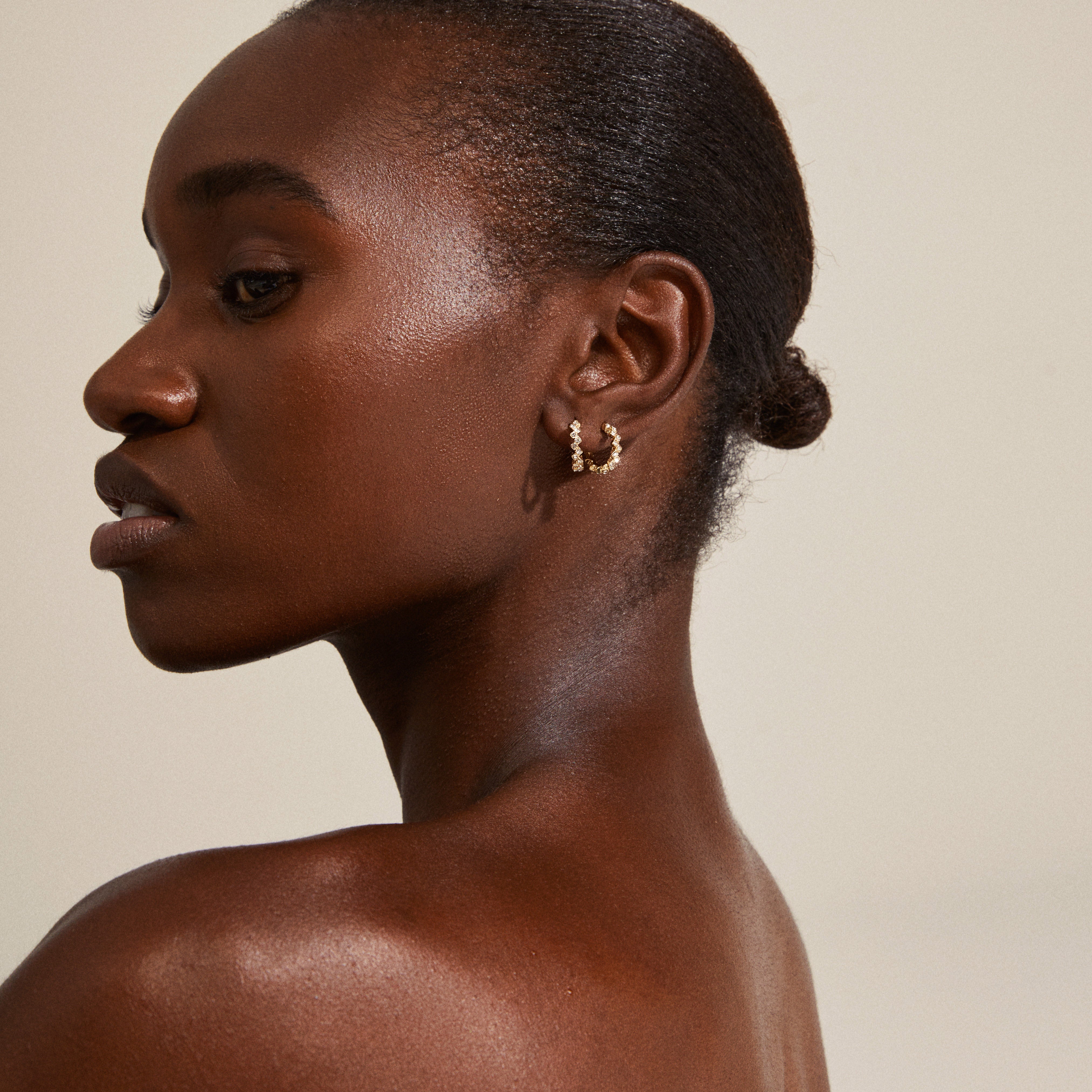 Close-up of a woman's ear adorned with ESTER crystal hoop earrings, gold-plated, showcasing angular design and sparkling Preciosa crystals for an elegant, edgy look.