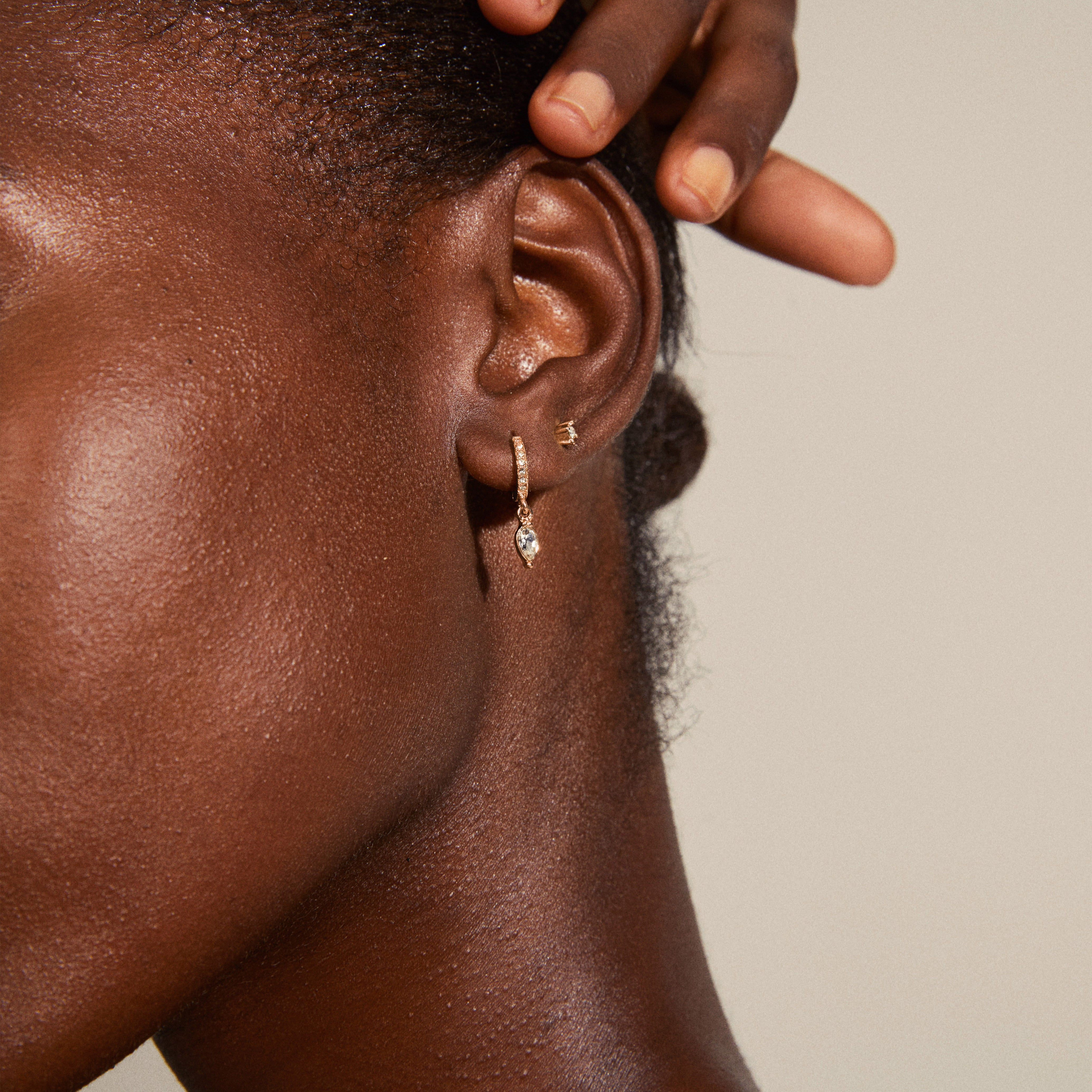 ELZA crystal earrings 2-in-1 set rosegold-plated, featuring close-up of teardrop pendant huggie hoops and crystal ear studs on a woman's ear.
