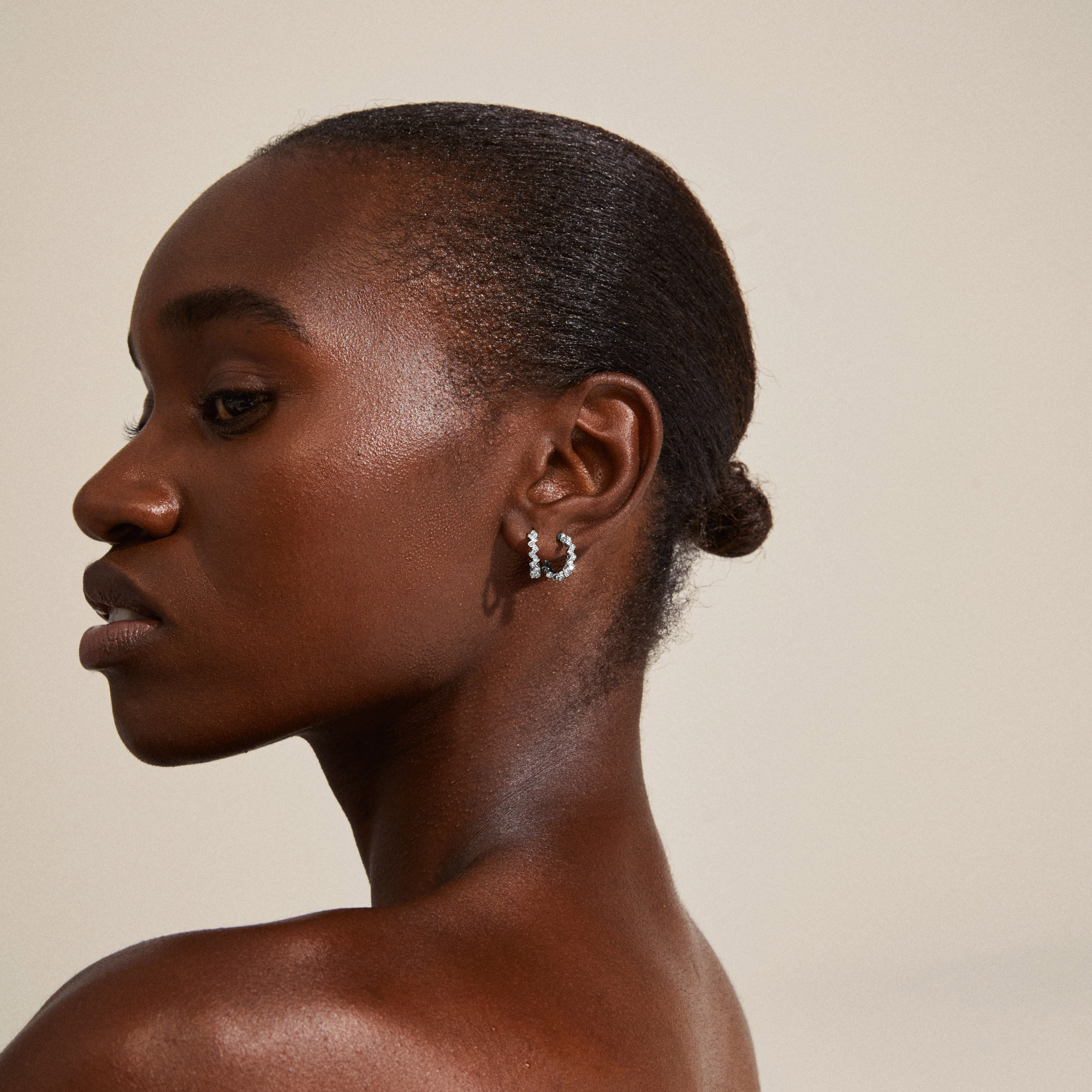 Close-up of a woman's ear adorned with silver-plated ESTER crystal hoop earrings, showcasing their angular design and sparkling Preciosa crystals.