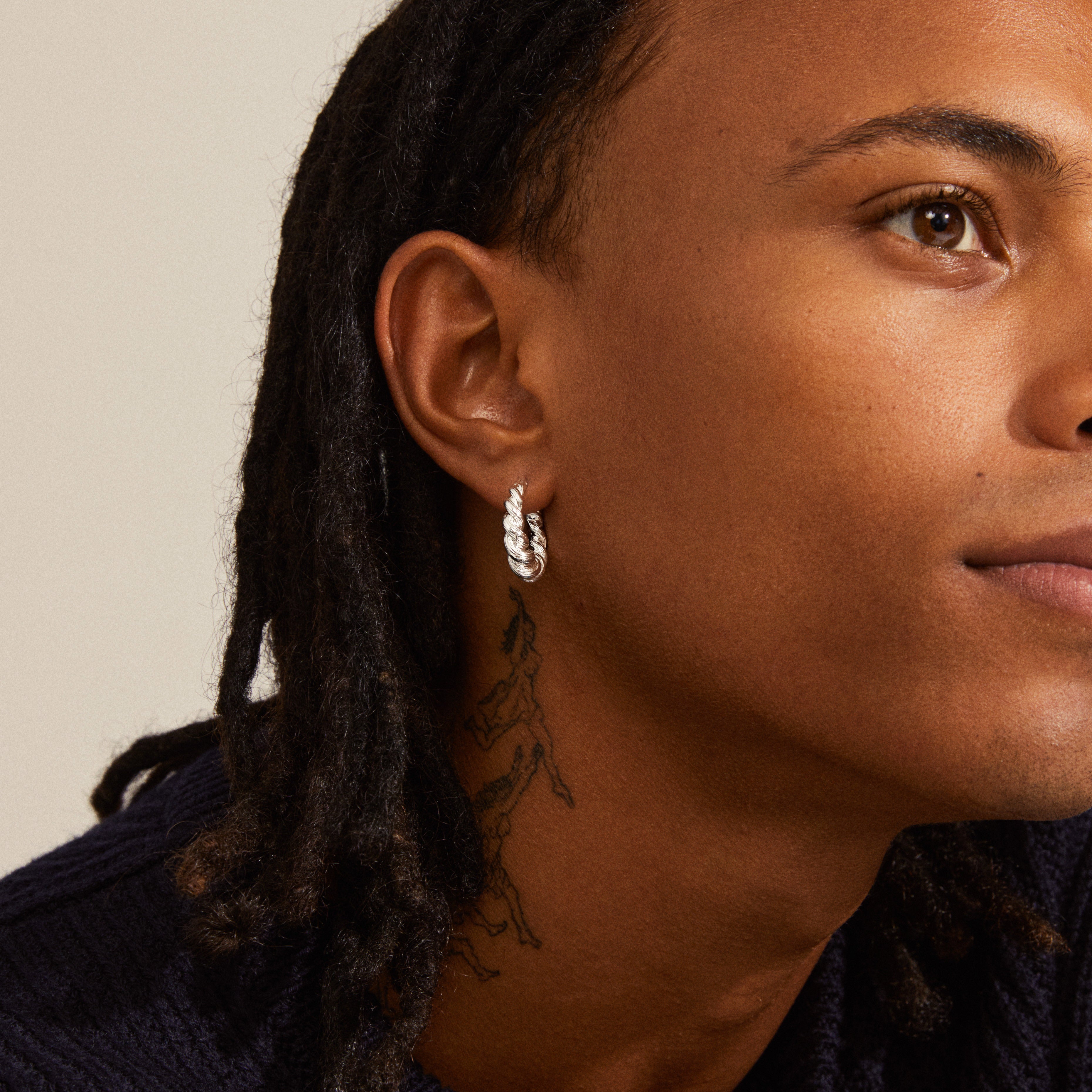 EILEEN twirl hoop earrings, silver-plated, showcased close-up on an ear, featuring intricate twisted design inspired by waves, capturing a boho essence.