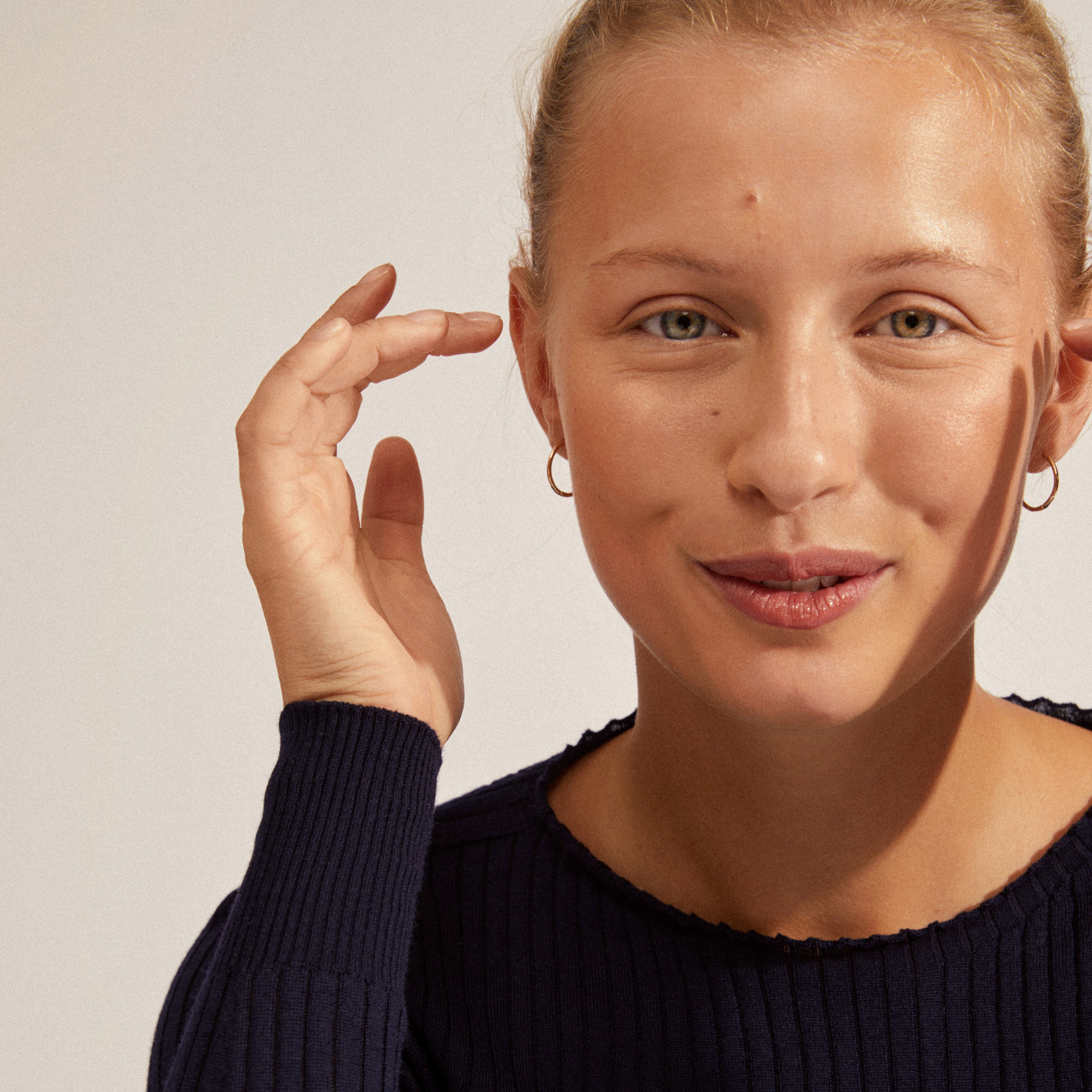 Woman wearing EANNA medium hoops gold-plated earrings, showcasing elegant design with a secure click lock, highlighting Pilgrim's blend of timeless and trendy Scandinavian jewelry.