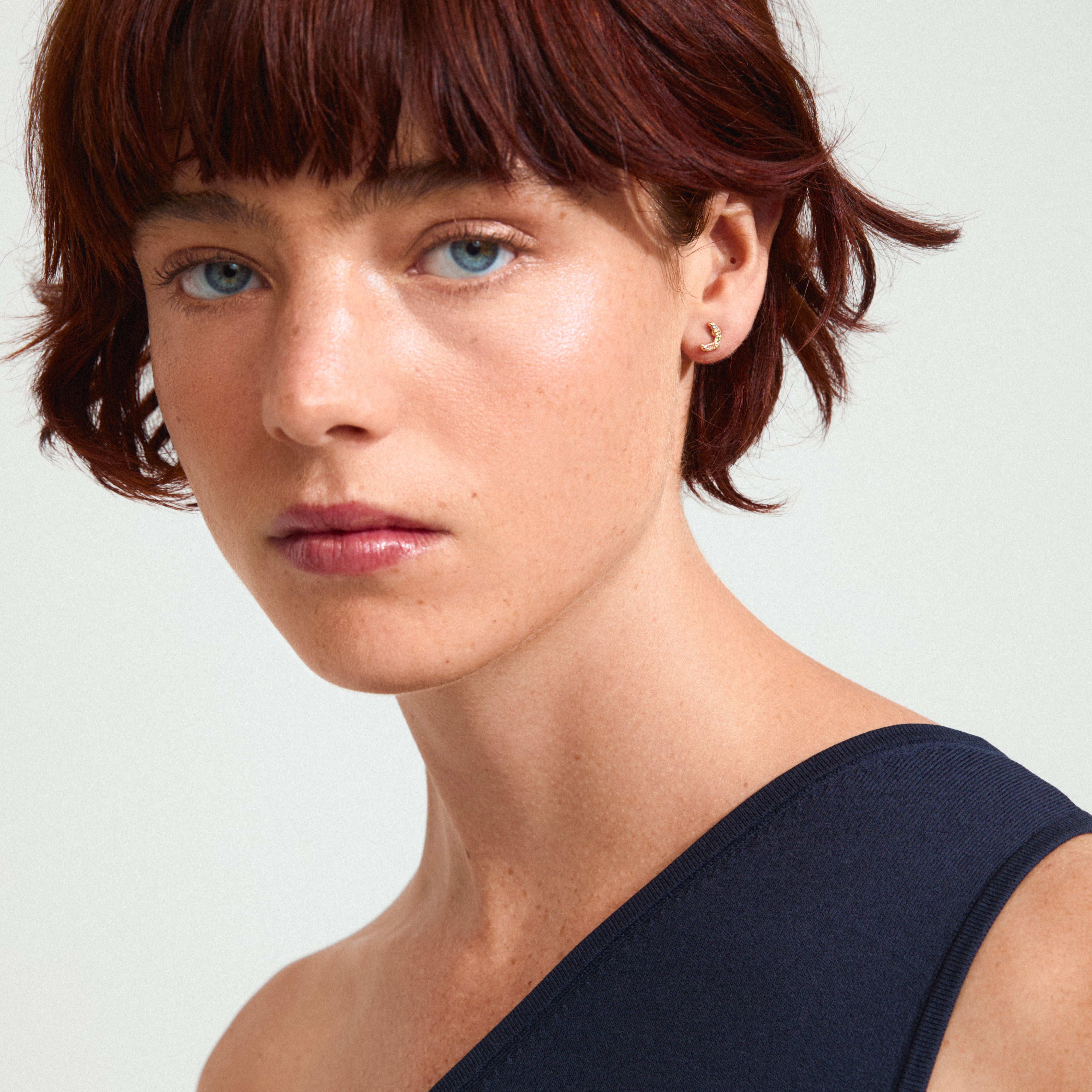 KORA earrings gold-plated with colorful Preciosa crystals, showcased on a woman with short red hair, highlighting trendy, asymmetrical styling.