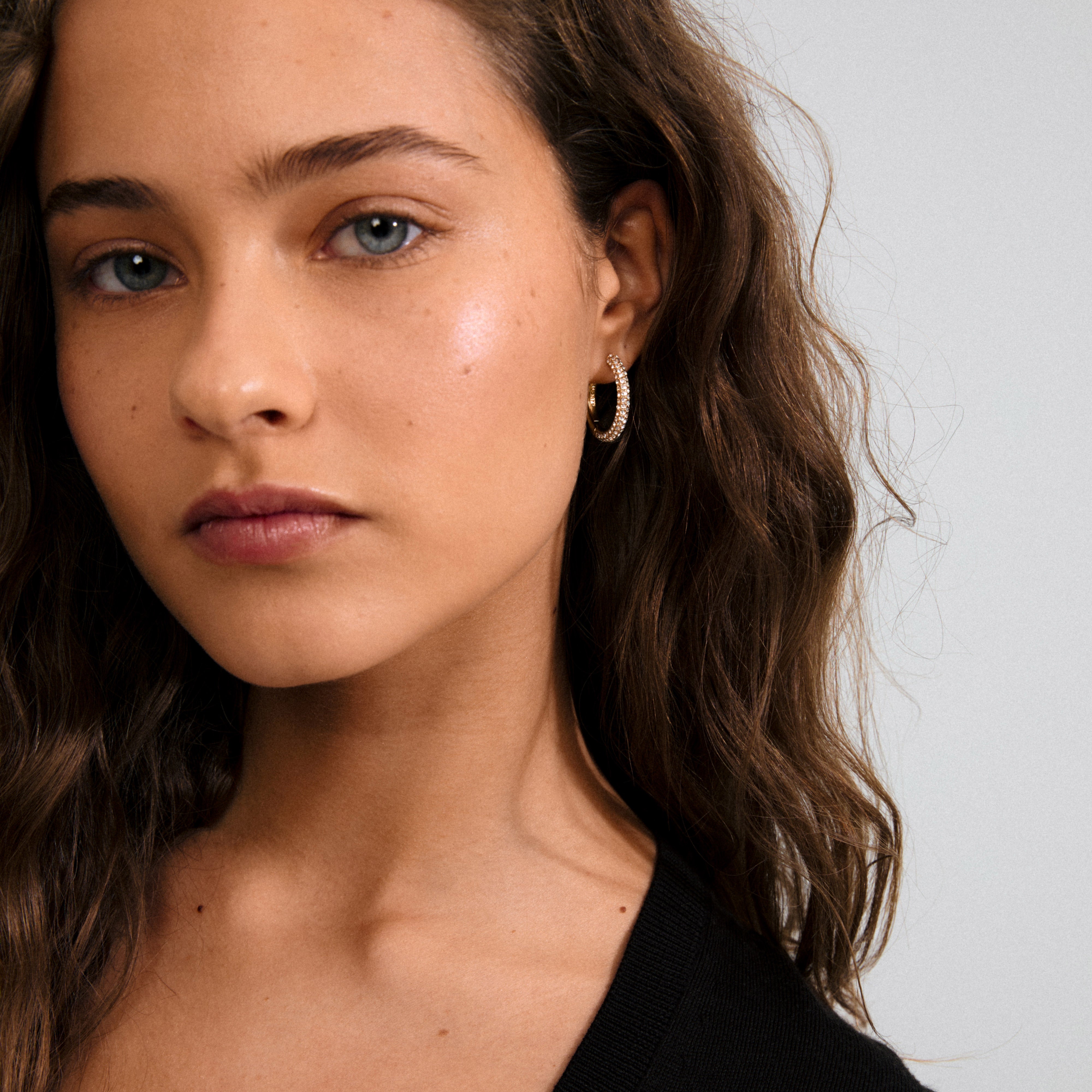 TATUM large hoops gold-plated with sparkling Preciosa crystals, perfect for day-to-night wear. Features snap locks, made from 97% recycled materials, offering style and comfort.