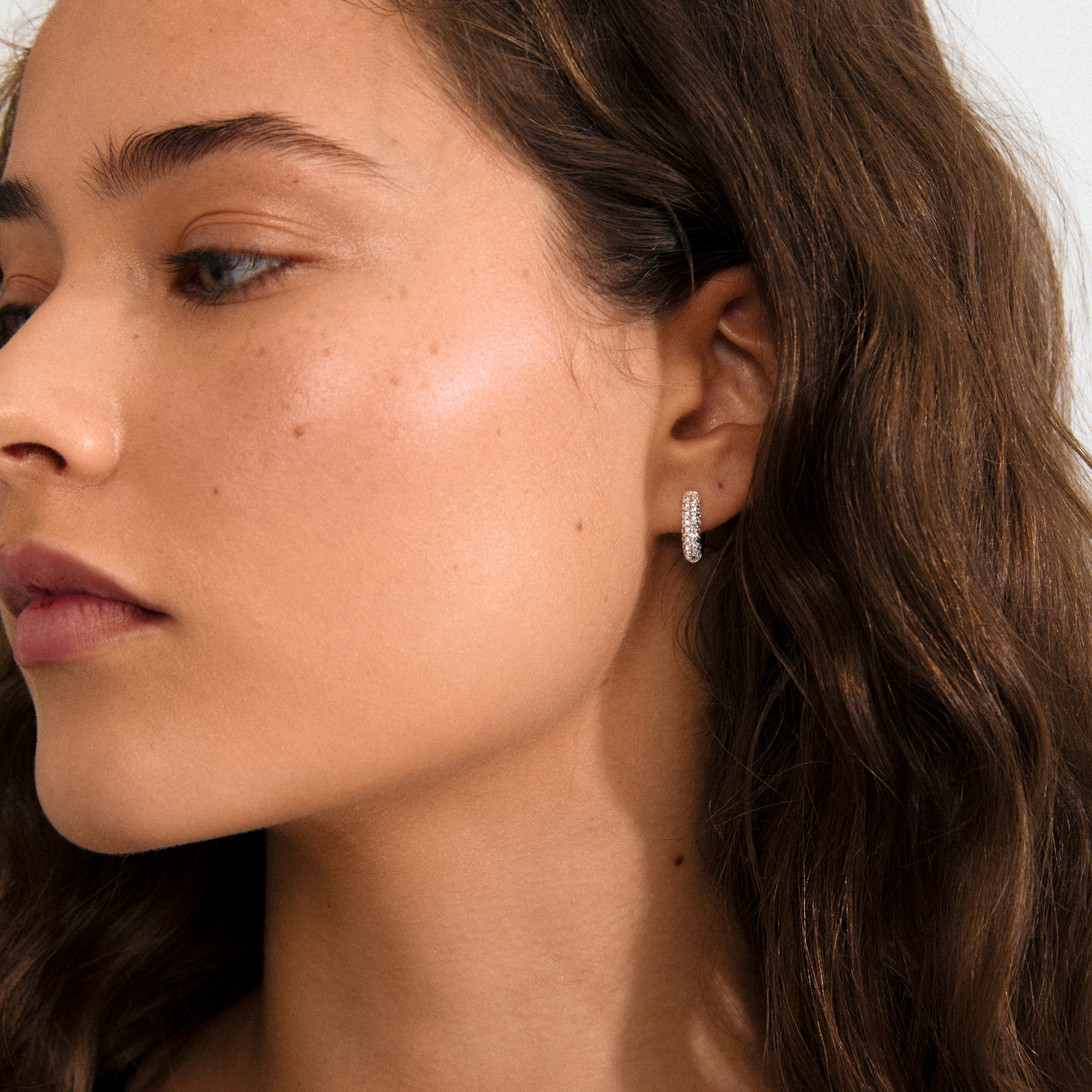 TATUM small hoops silver-plated, featuring sparkling Preciosa crystals, offer understated luxury and versatility with easy click clasps, crafted from 96% recycled material.